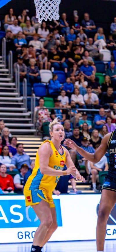 UC Capitals player driving to the basket for a layup during a WNBL game.