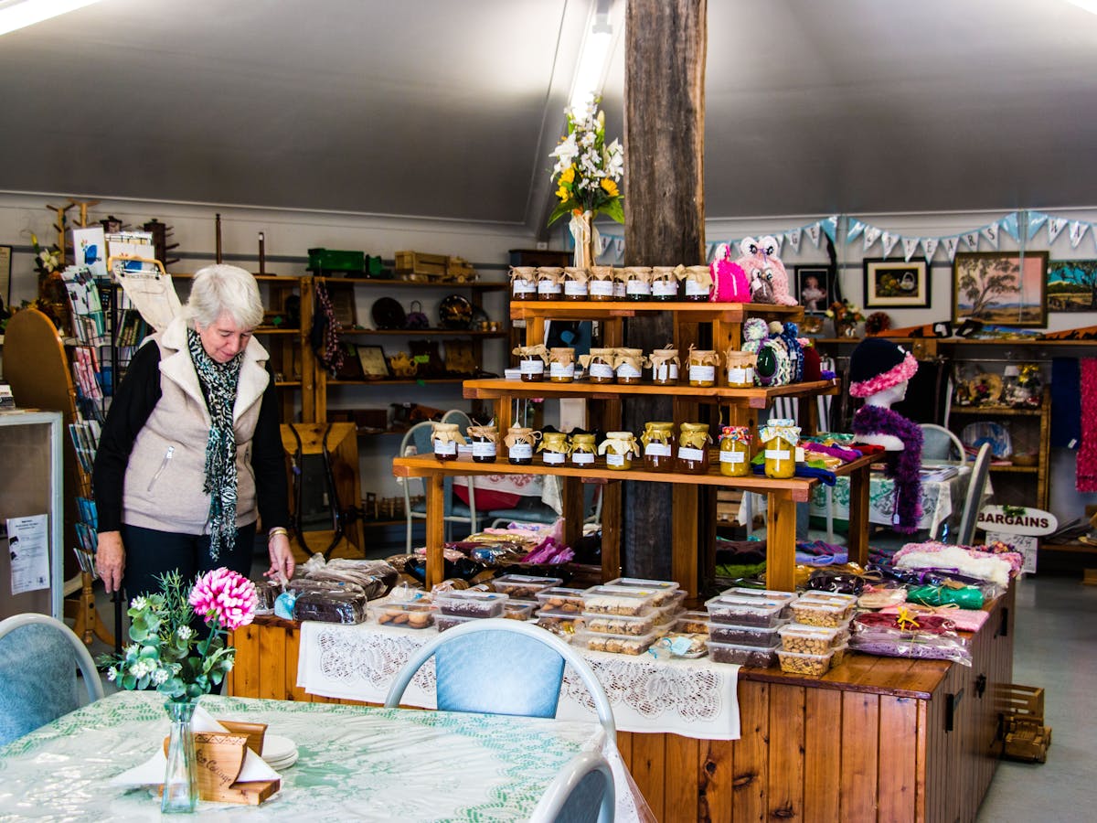 A room with displays of jams, preserves, packaged baked goods. A woman is looking at the display.