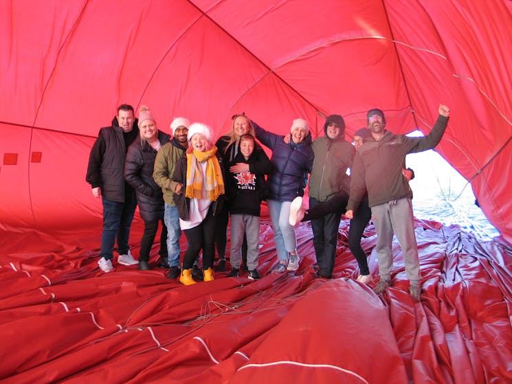 Passengers waving inside the balloon after landing. Red fabric