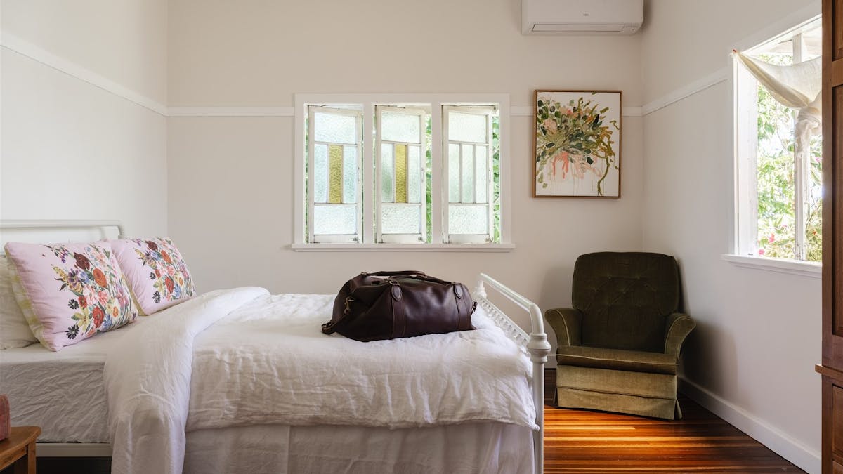 Bedroom with antique chair in the corner and white linen sheets.