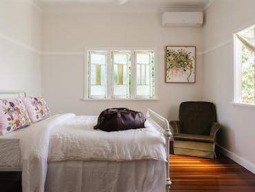 Bedroom with antique chair in the corner and white linen sheets.