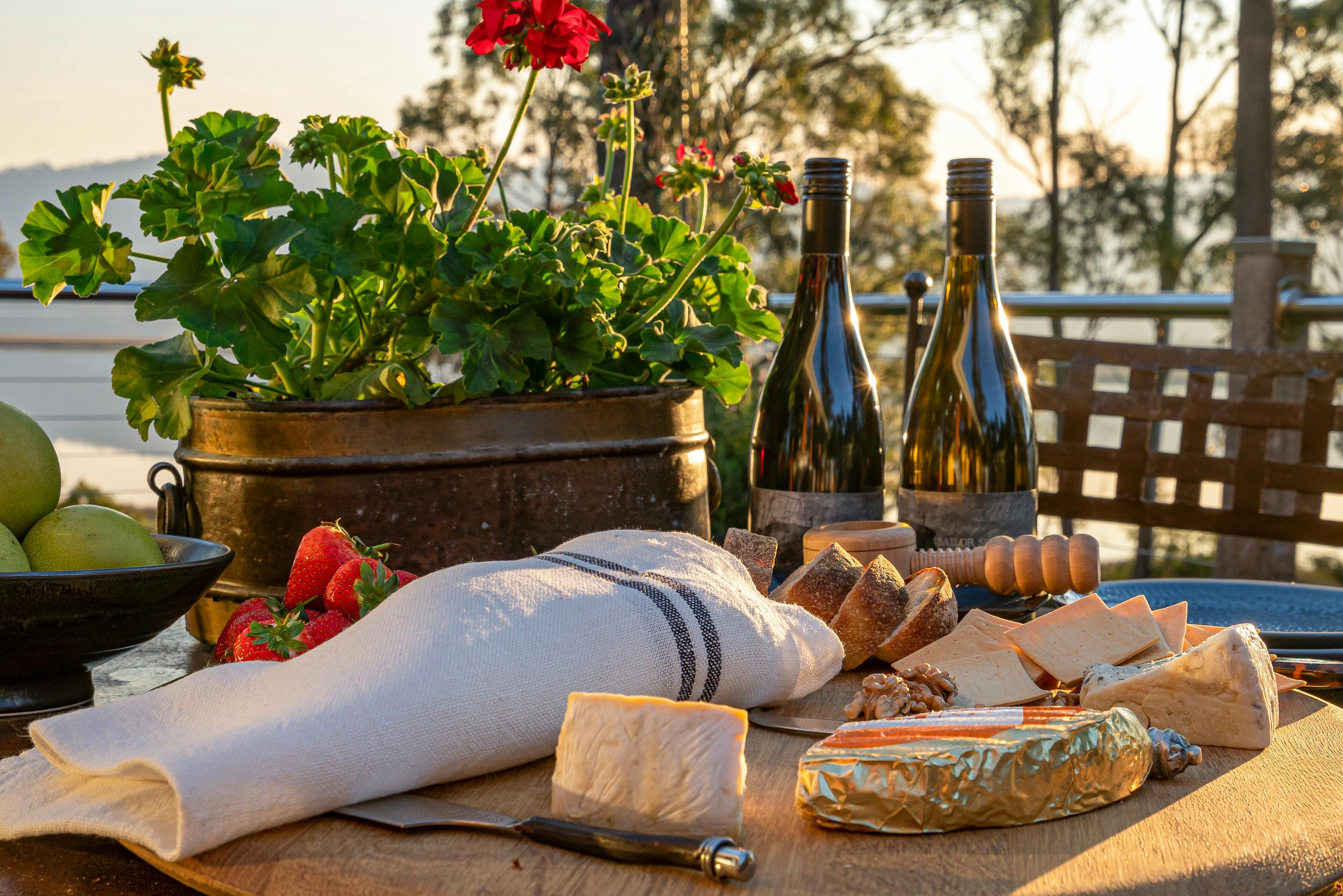 Two bottles of pinot noir and a cheese spread laid out for outdoor dining at Huon River Hideaway