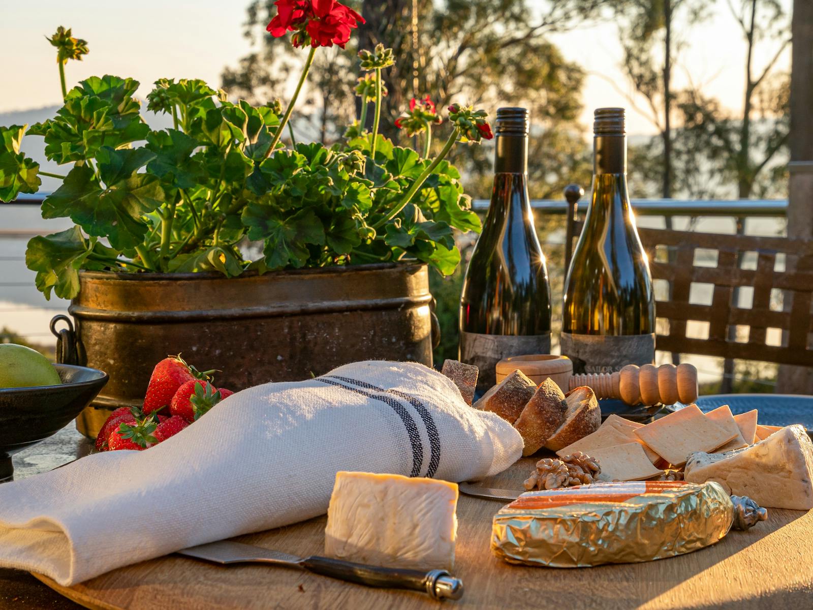 Two bottles of pinot noir and a cheese spread laid out for outdoor dining at Huon River Hideaway