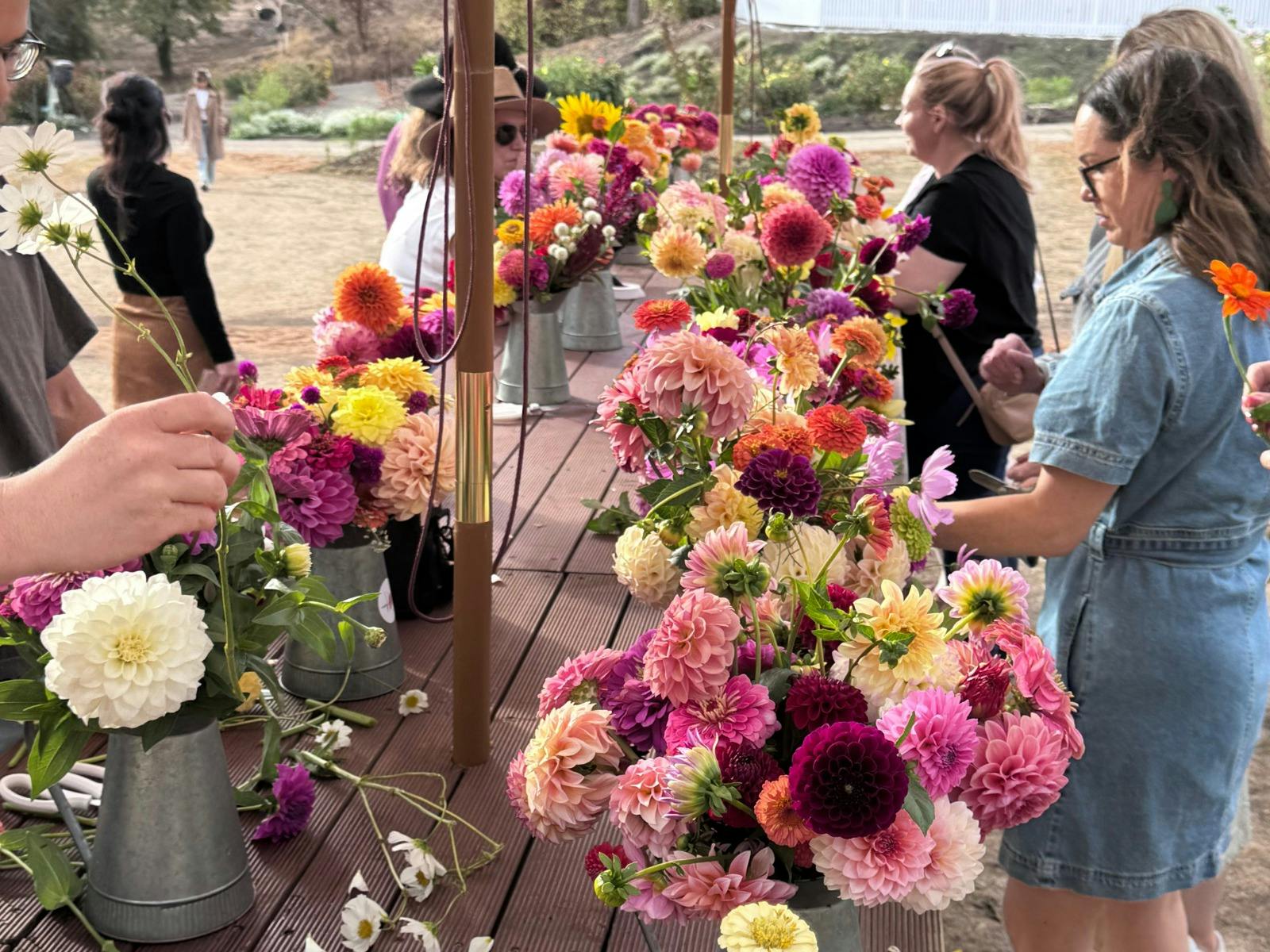 Visitors arranging colourful dahlias and wildflowers in rustic vases