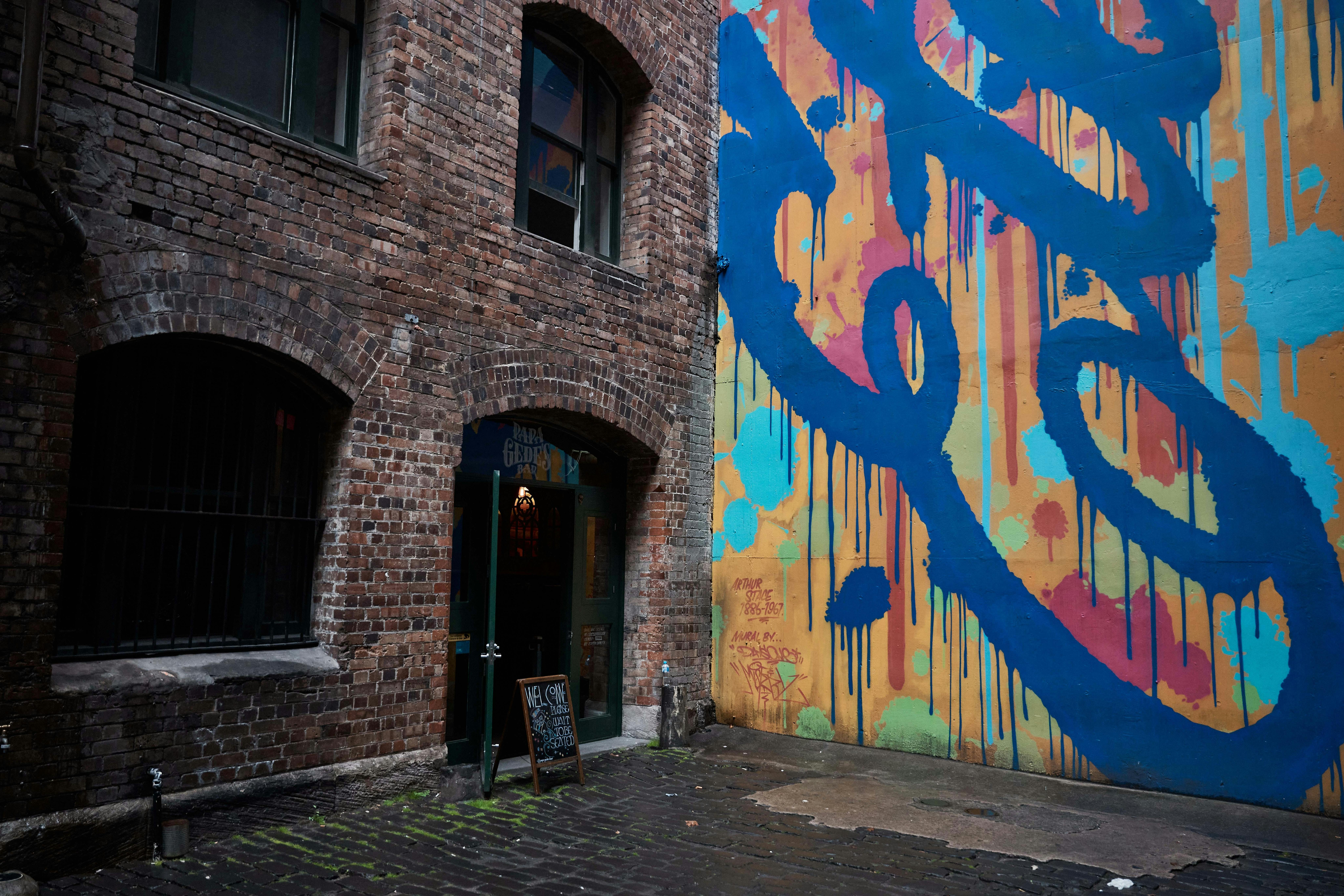 The corner of a courtyard with a large mural on one side, and the entrance to a bar on the other.