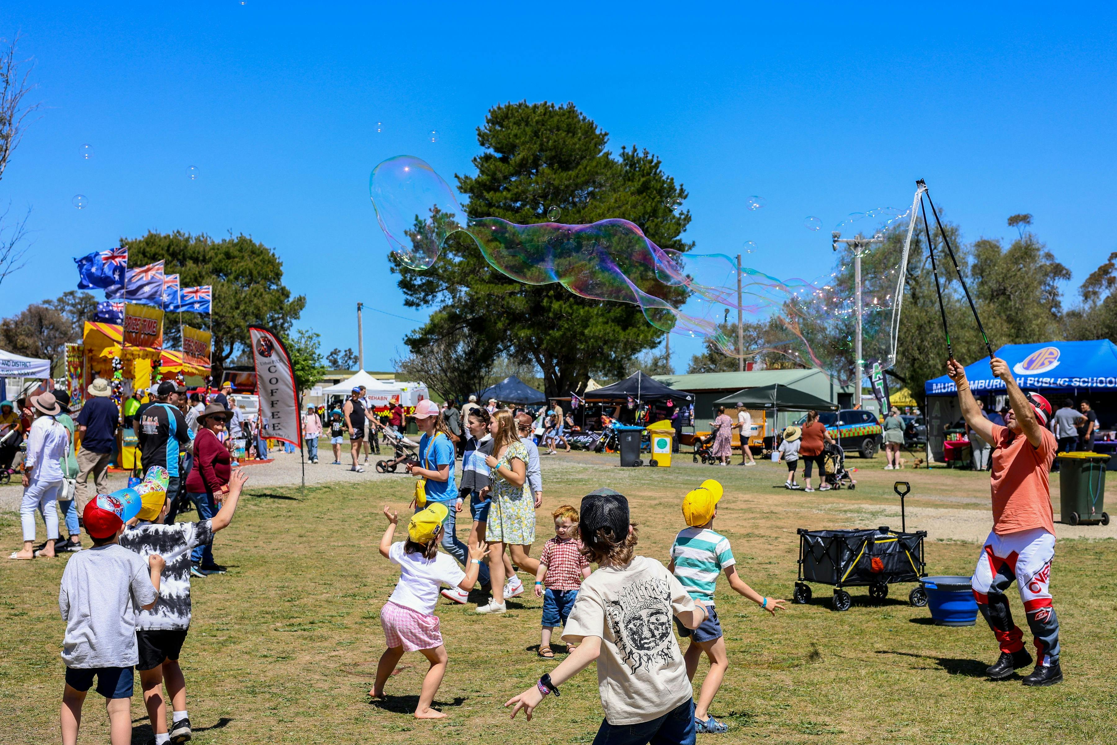 Roaming performer making bubbles for the kids to chase. More rides and markets in back.