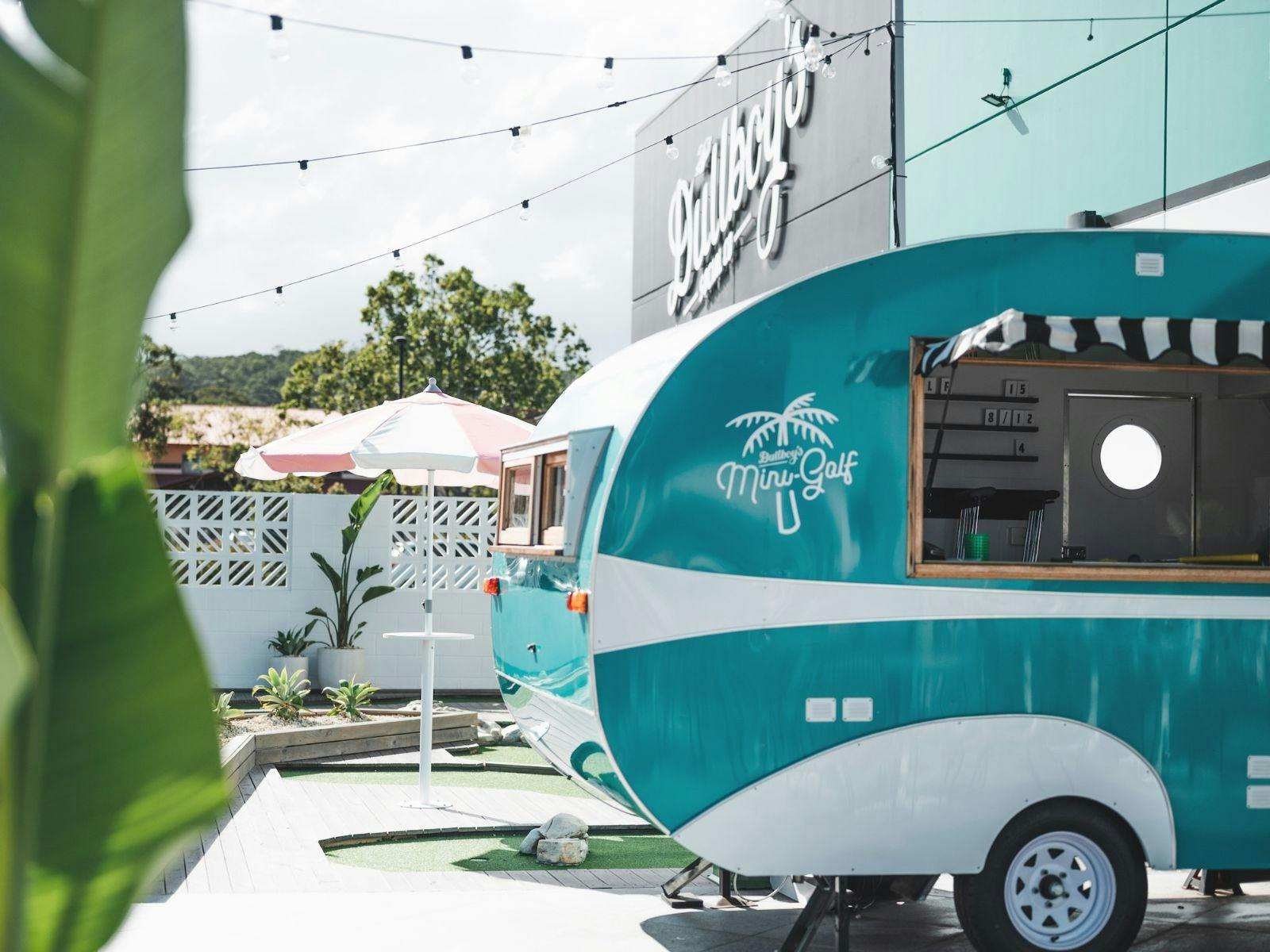 A teal van on a mini golf course