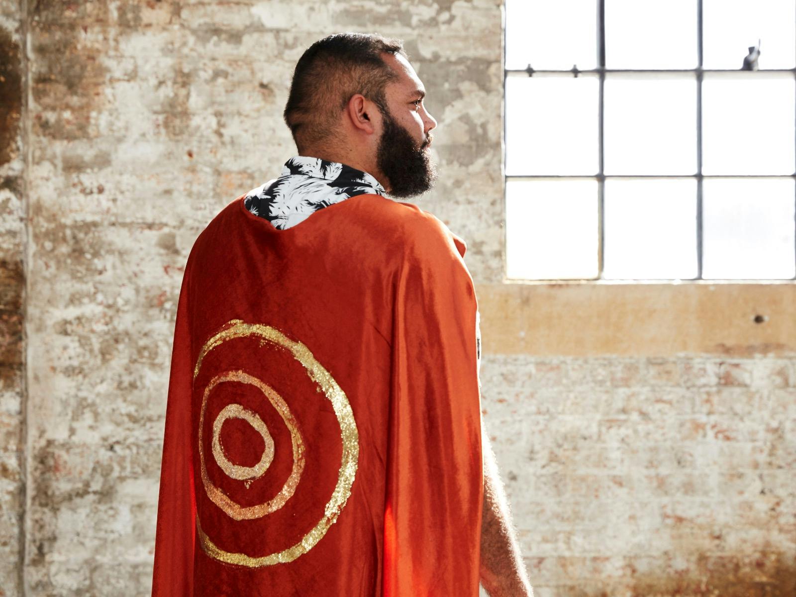 Dennis Golding wearing  a red and gold cape