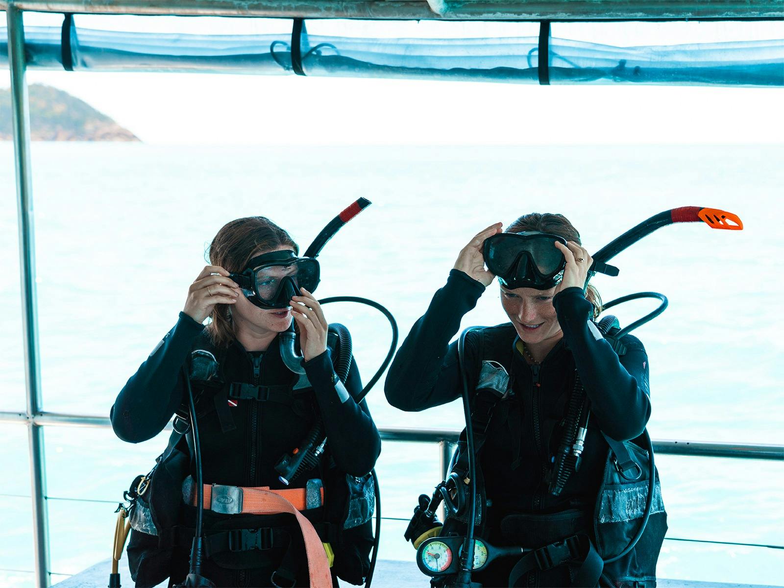 Two females preparing to go Scuba Diving, fitting their mask to their faces