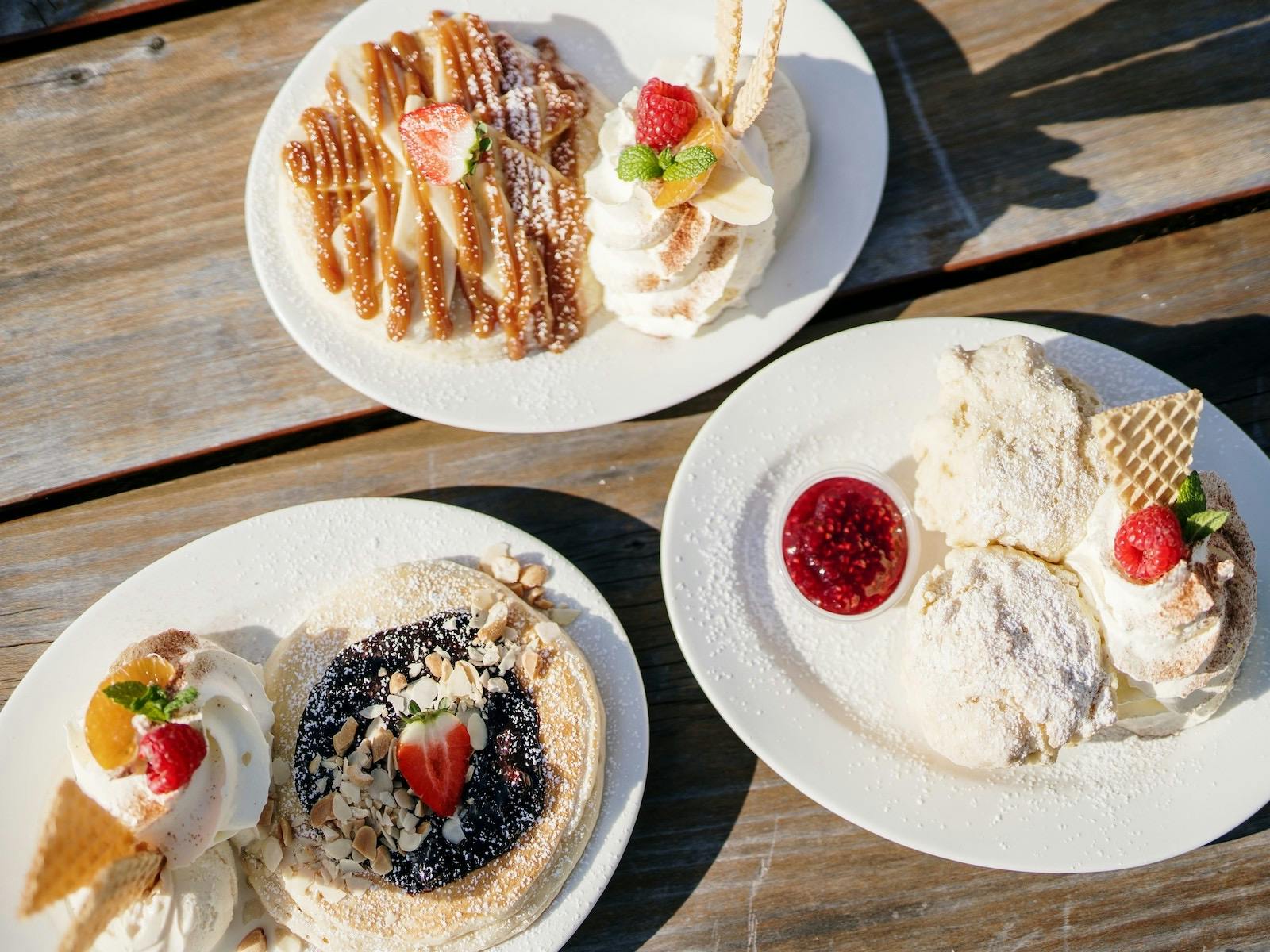 Three plates with various types of pancakes.