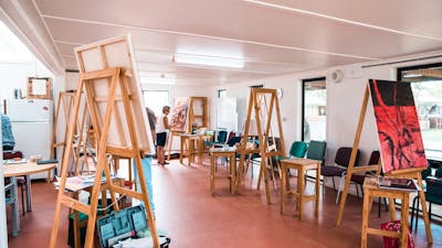 Several easels holding large canvases are set up in a large room.