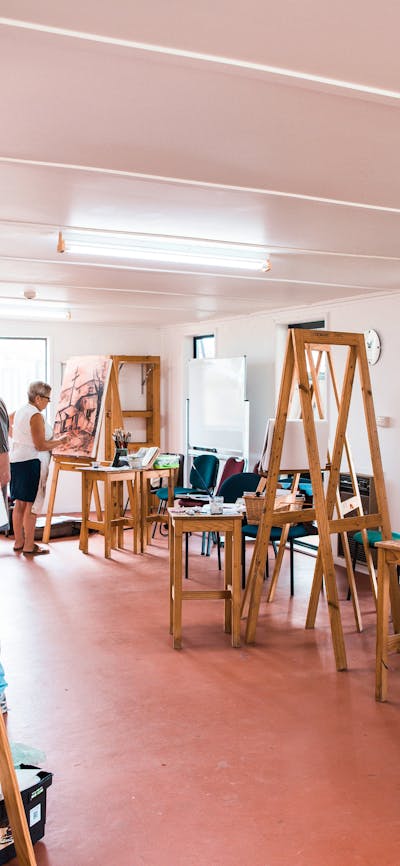 Several easels holding large canvases are set up in a large room.