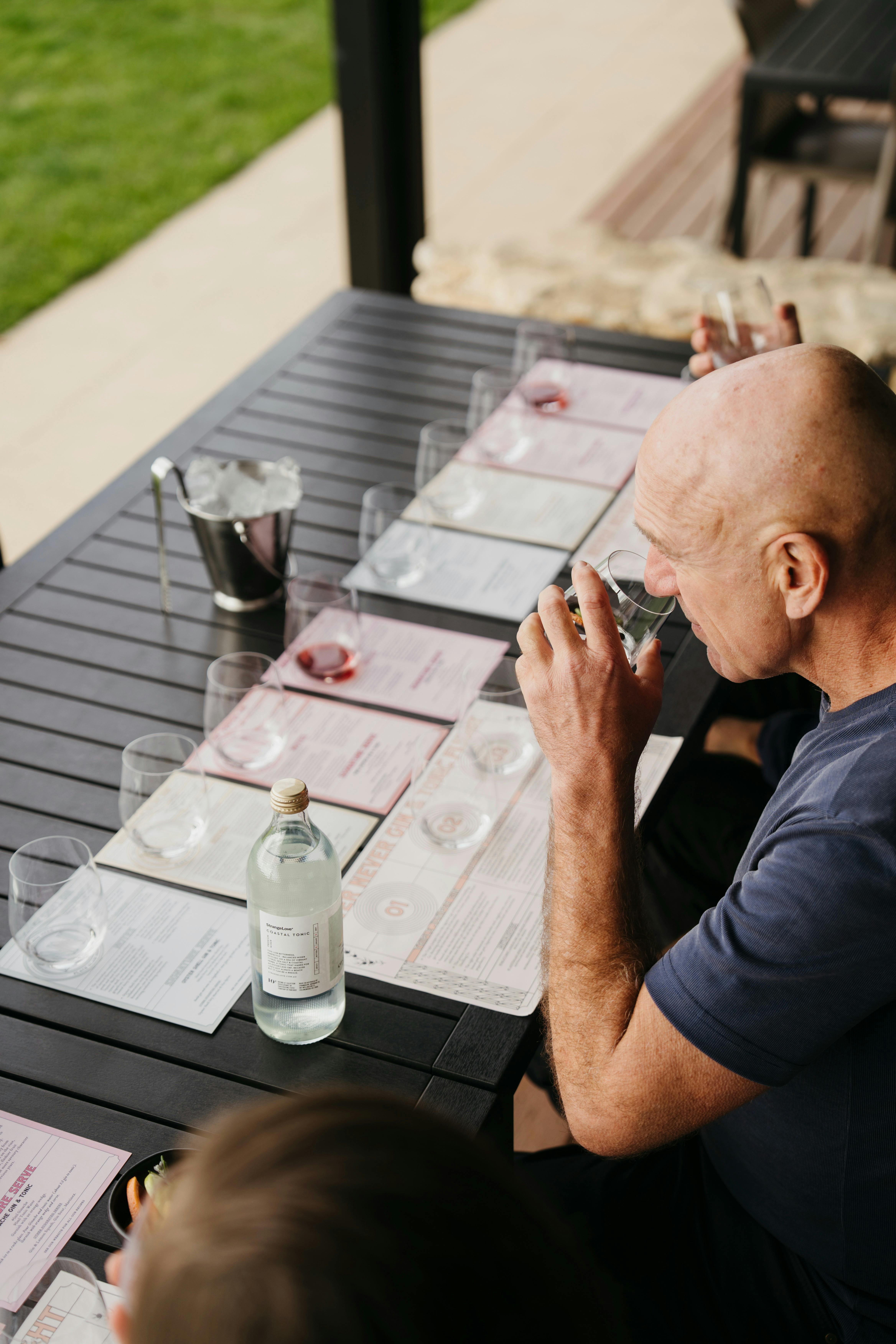 Man smelling a gin with a tasting panel in front of him on a black table.