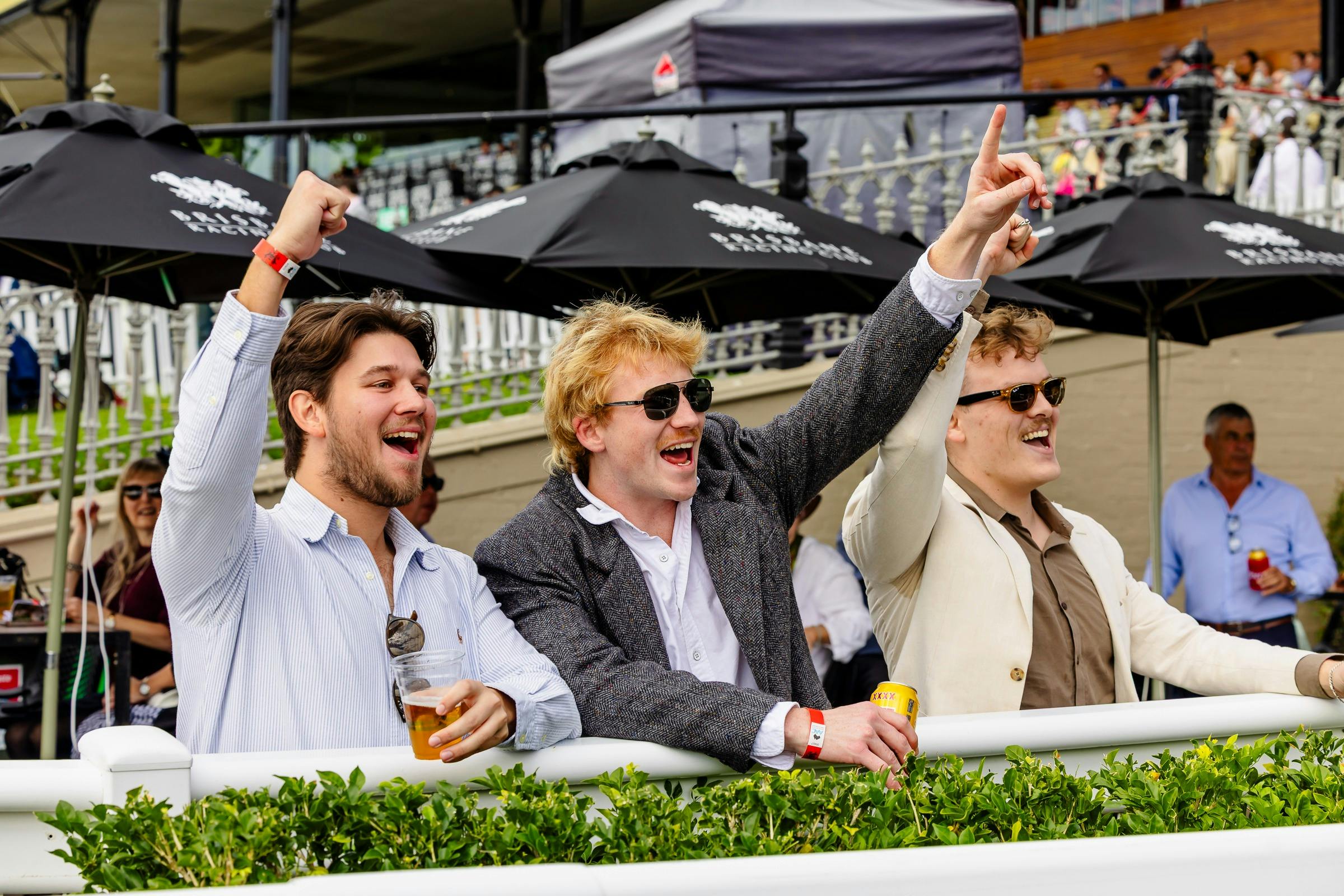 Three male friends celebrate a win at Eagle Farm Racecourse