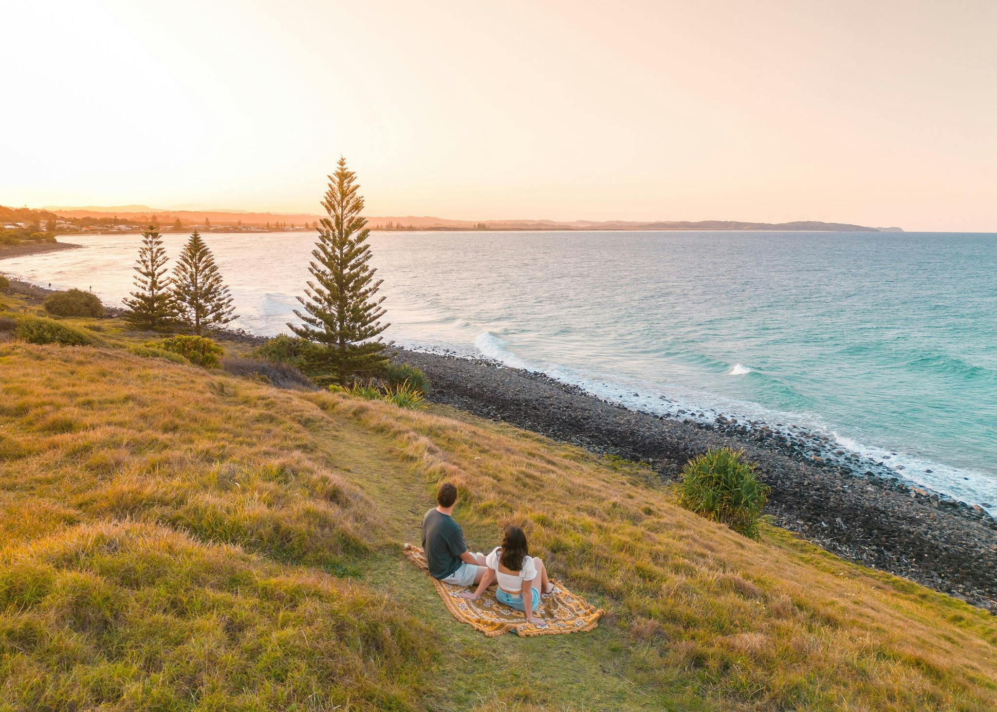 Paar mit Blick auf den Strand von einem Aussichtspunkt aus