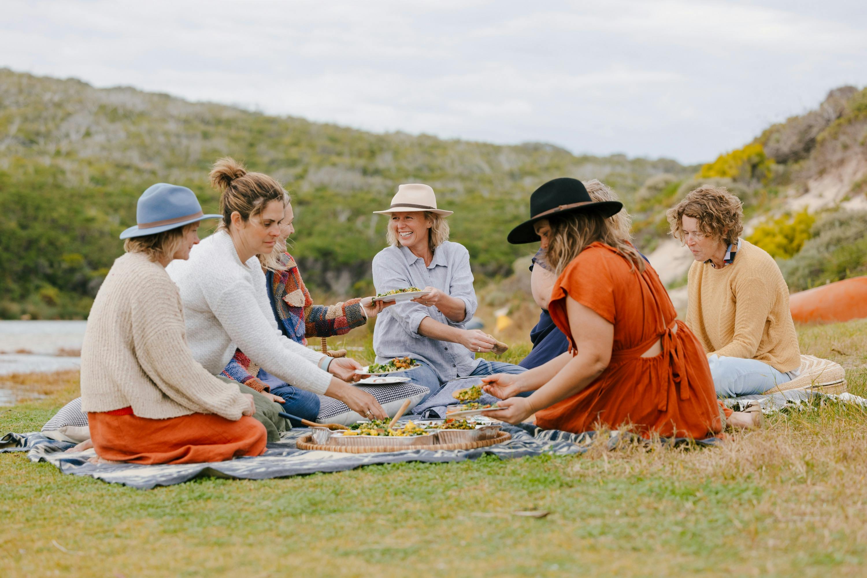 Ladies sit around a pic Nic sharing food and laughing