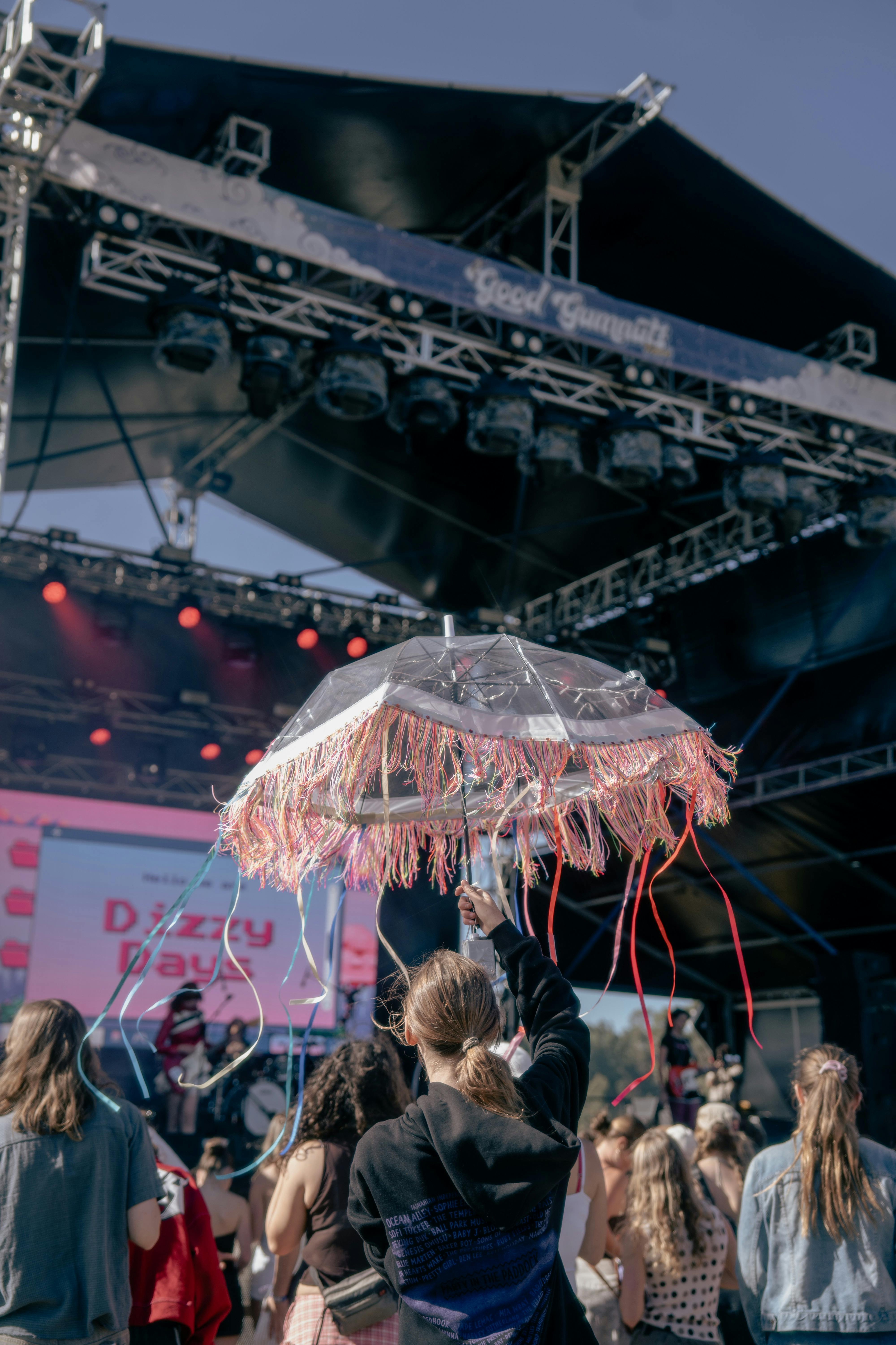 Festivalgoer holding a colourful umbrella doof stick in front of the stage at Good Gumnuts Festival.