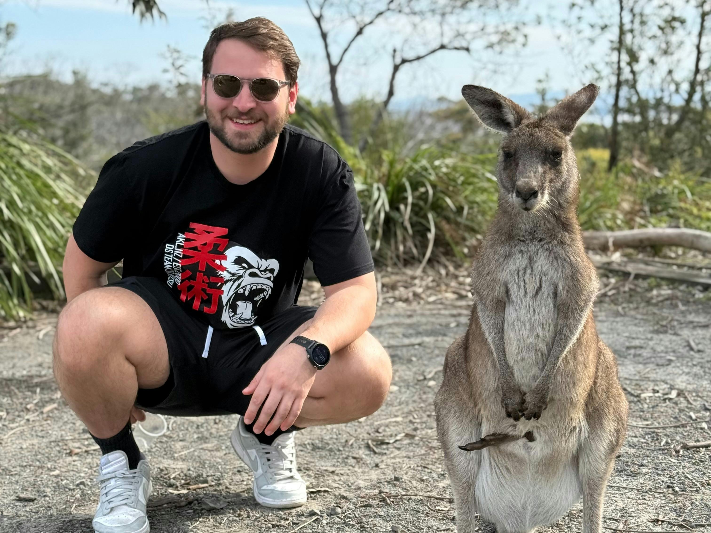 Man standing next to a wild kangaroo in New South Wales on a day tour from Sydney