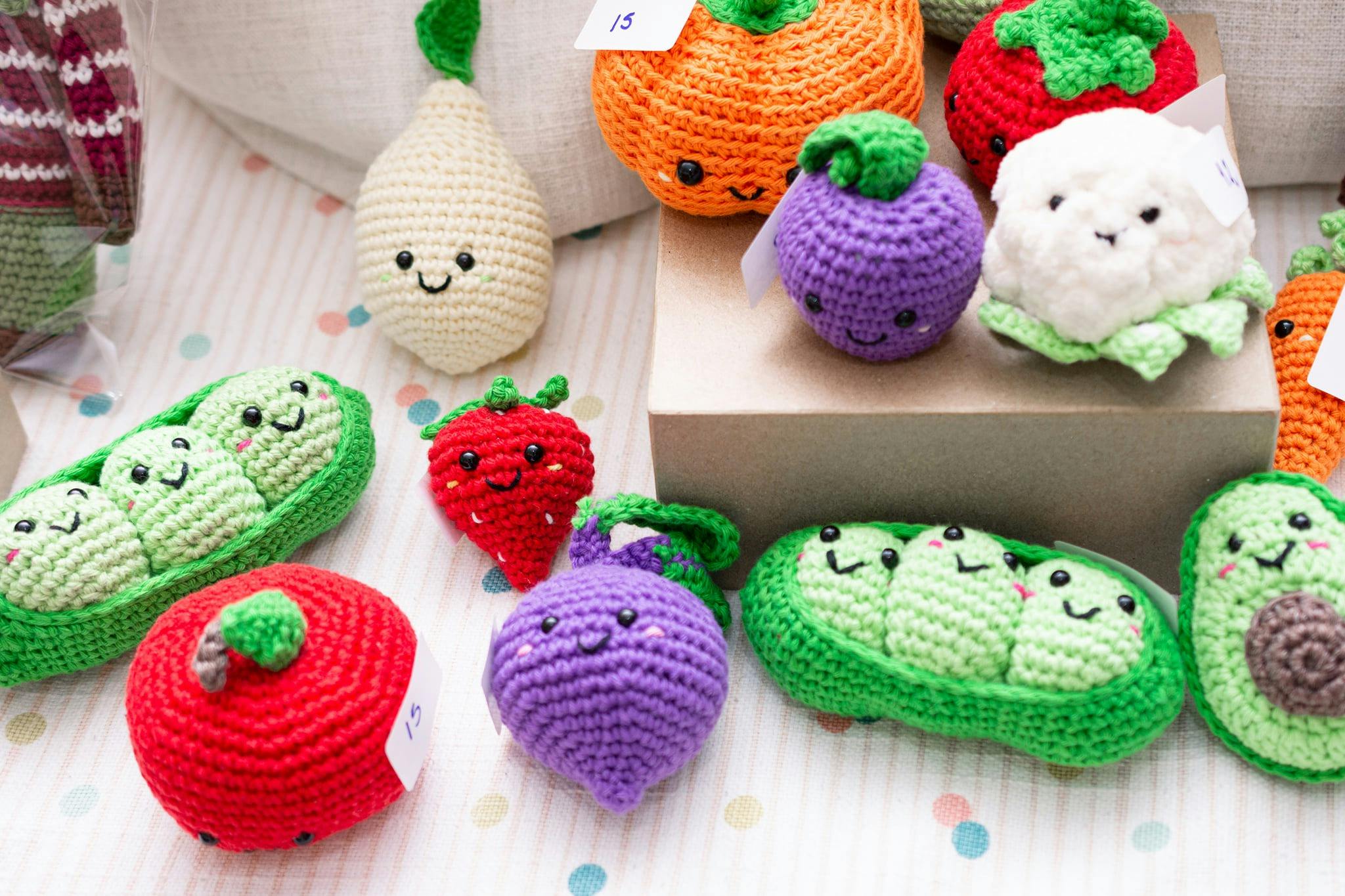 A closeup shot of crochet fruit and vegetables with smiling faces on them