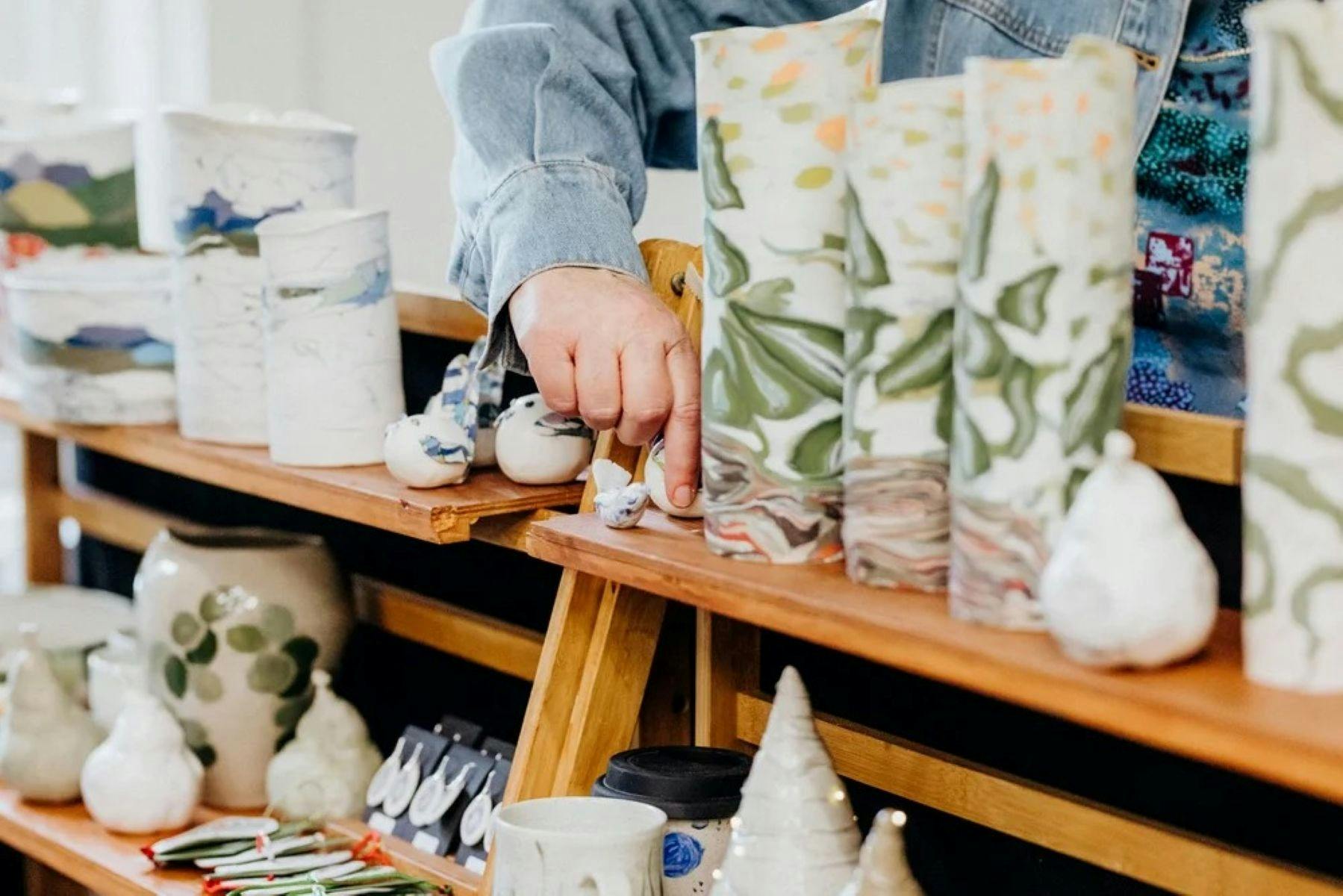 A hand touching some ceramic vessels on a market stall display