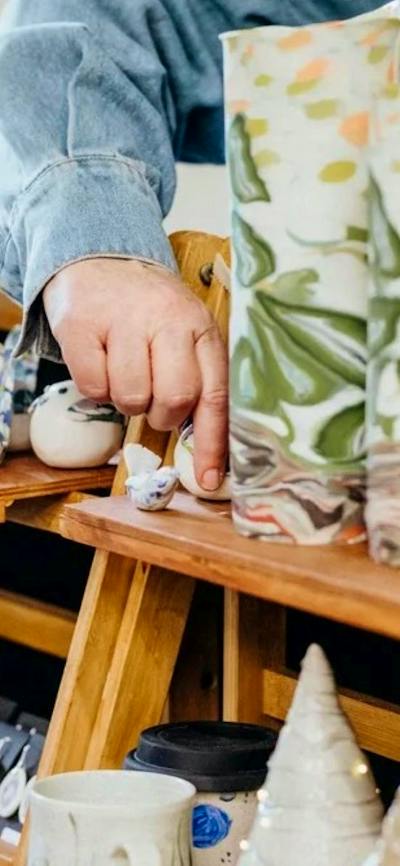 A hand touching some ceramic vessels on a market stall display