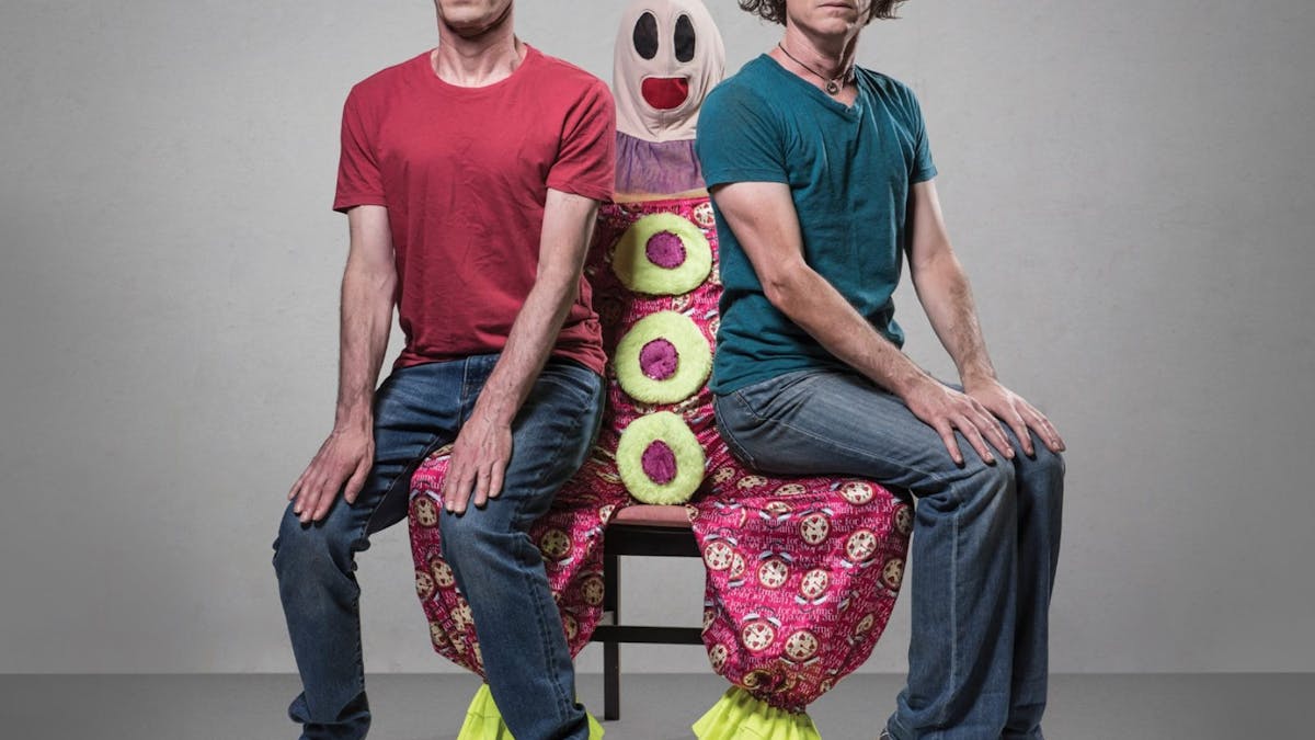 2 men red tshirt on left green on right sitting on a clown
