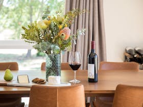 Dining table with cheese platter with a pear and bottle of wine and glass of wine