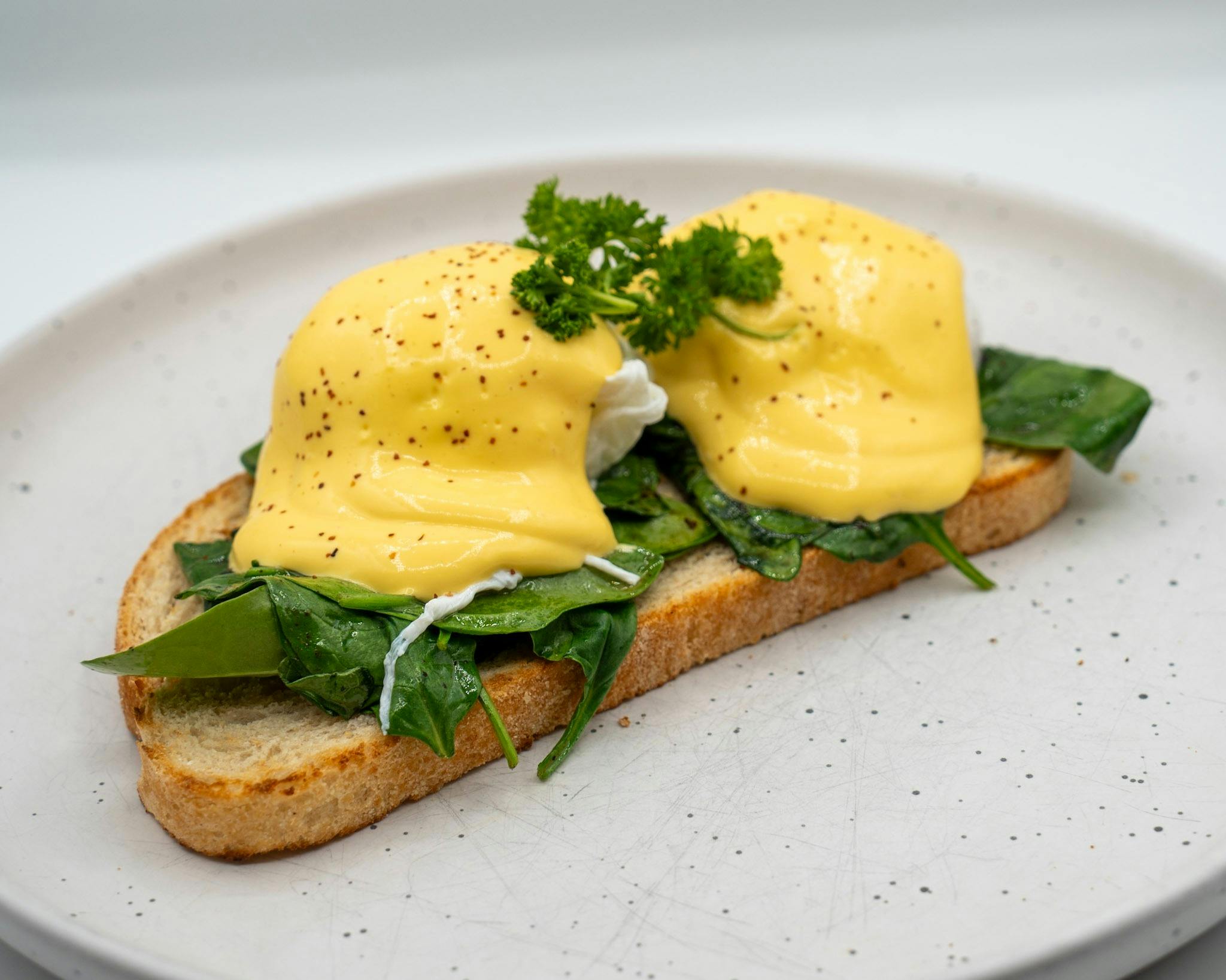 Two poached eggs topped with hollandaise sauce on toasted bread.