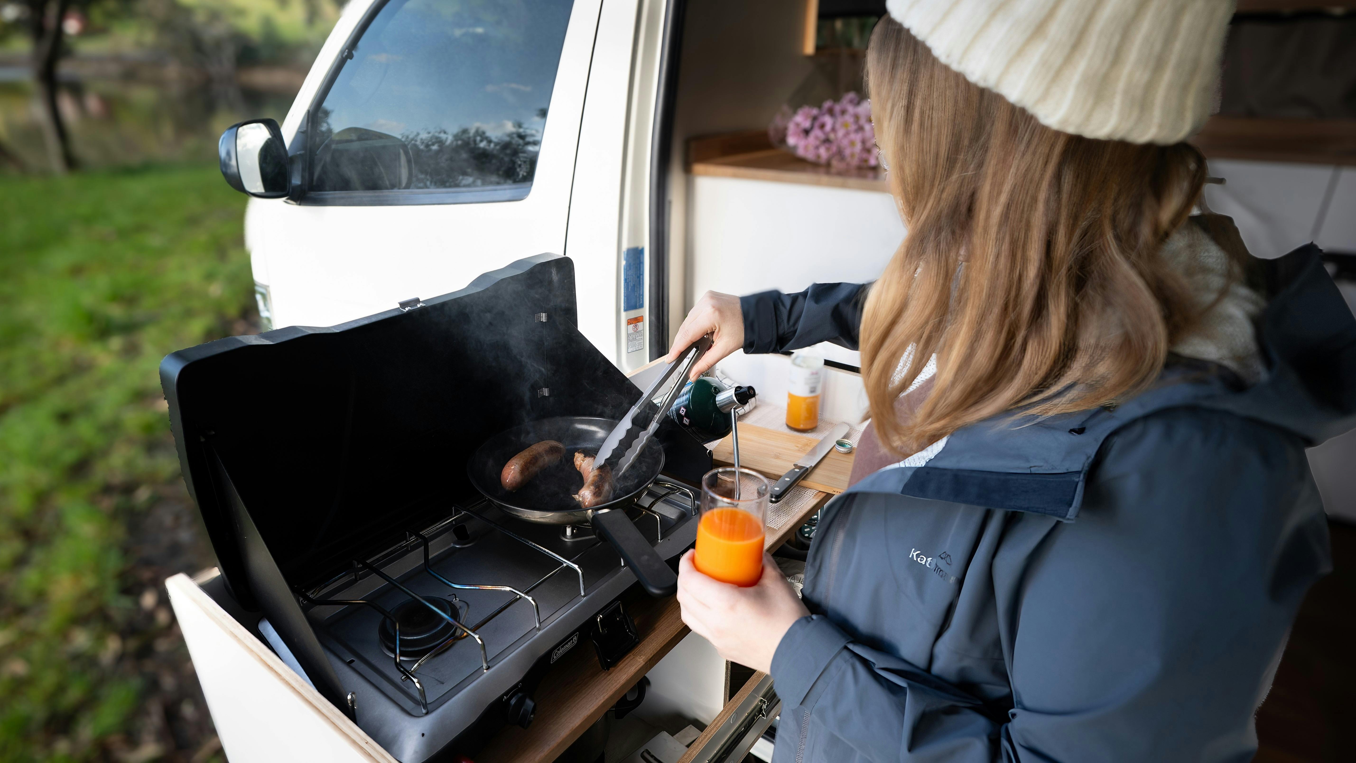 Preparing food in campervan slide out kitchen, relaxing outdoors in Tasmania.
