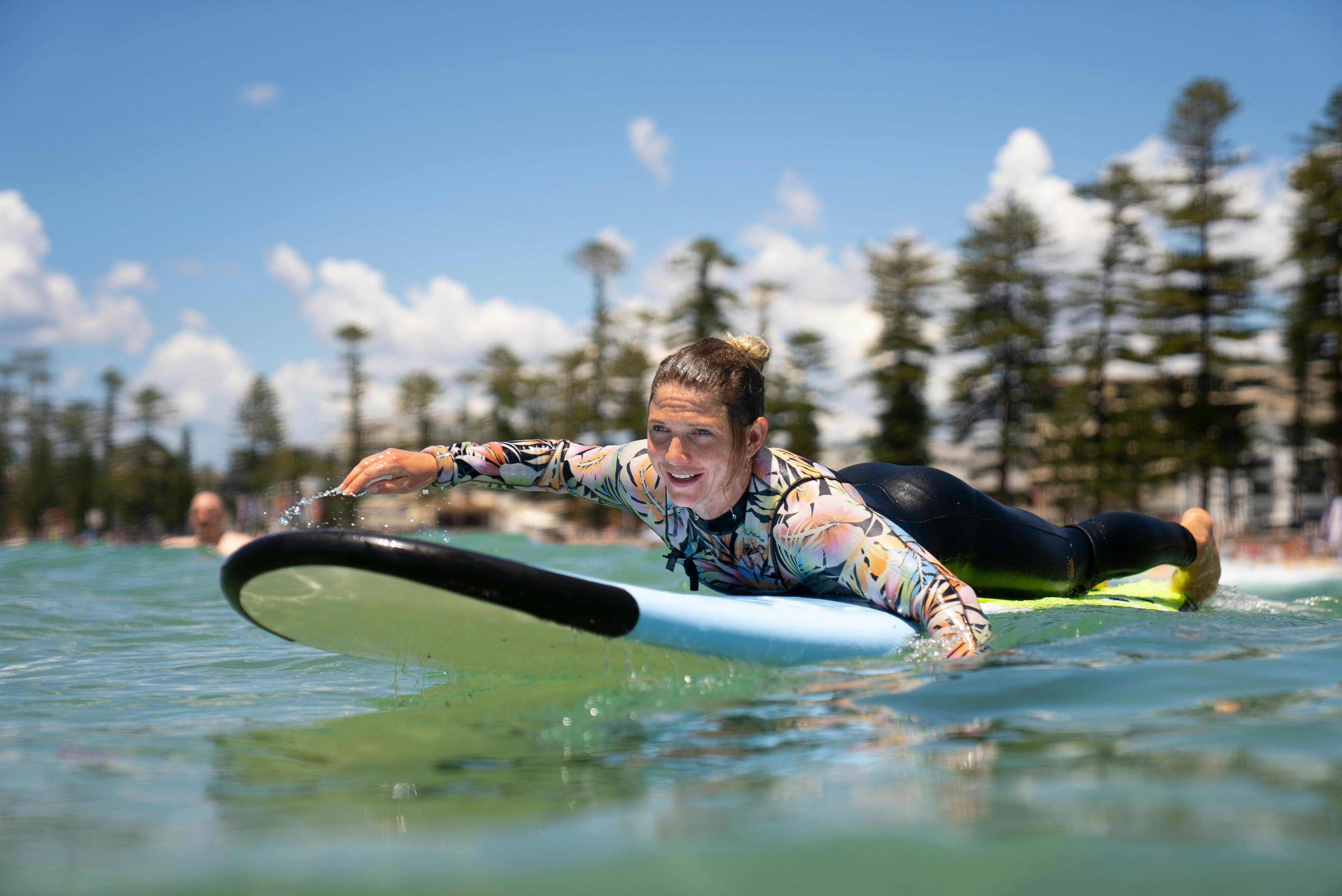Woman paddling at Manly Beach on a surfboard