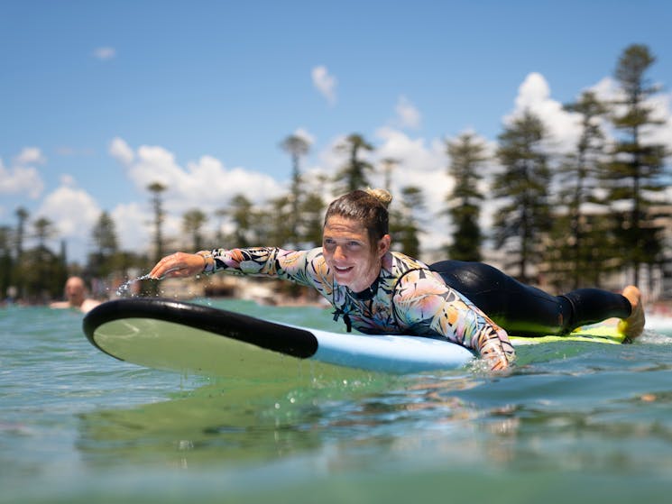 Woman paddling at Manly Beach on a surfboard