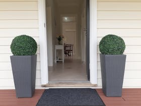 Front entry, 2 planters by front door, opened door, tiled entry, hall table, dining table and chairs