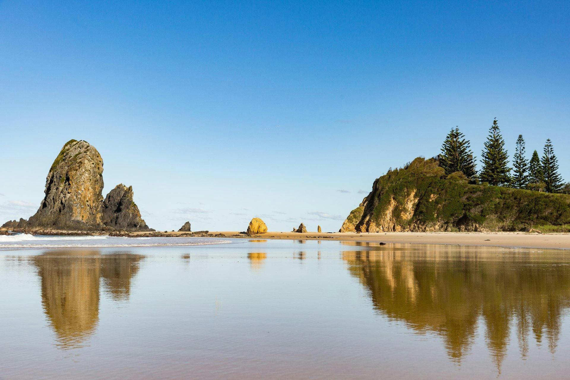 Viwe across the beach sand to large rock formations