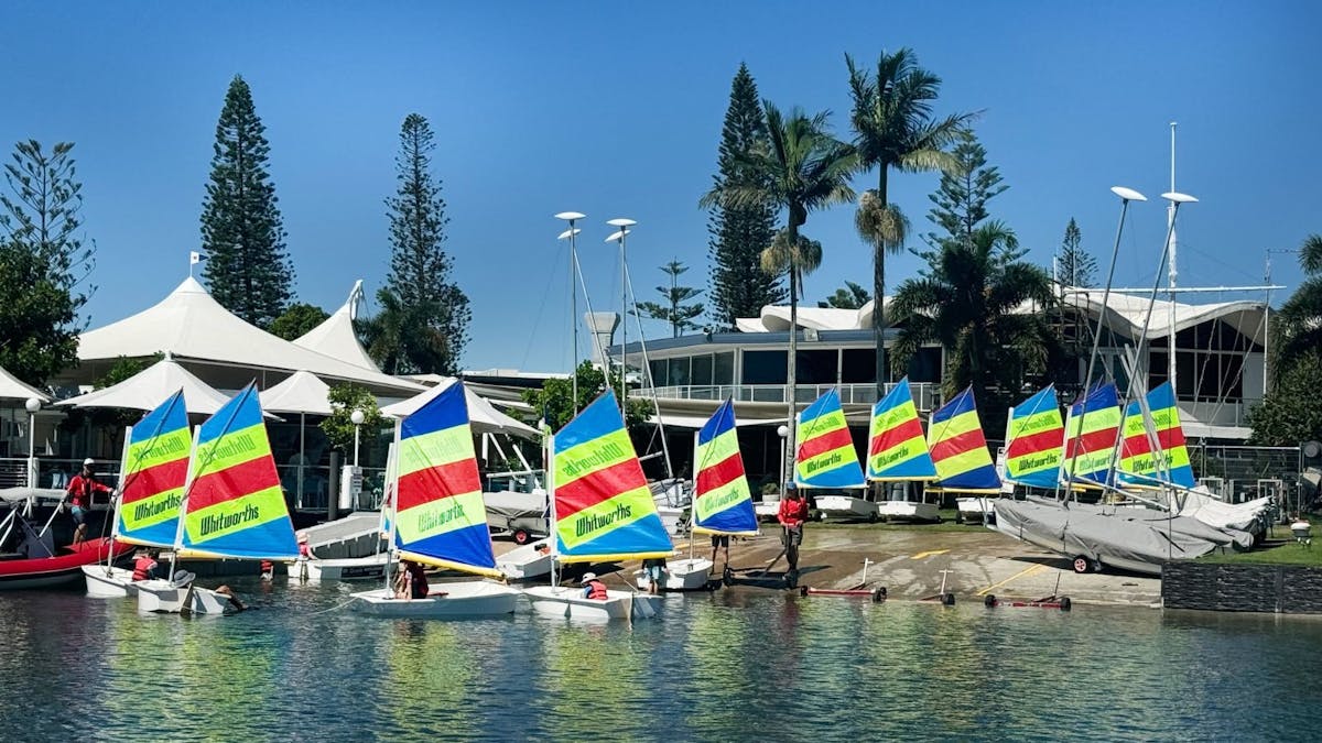 A group of youth launching sailboats at a boatramp