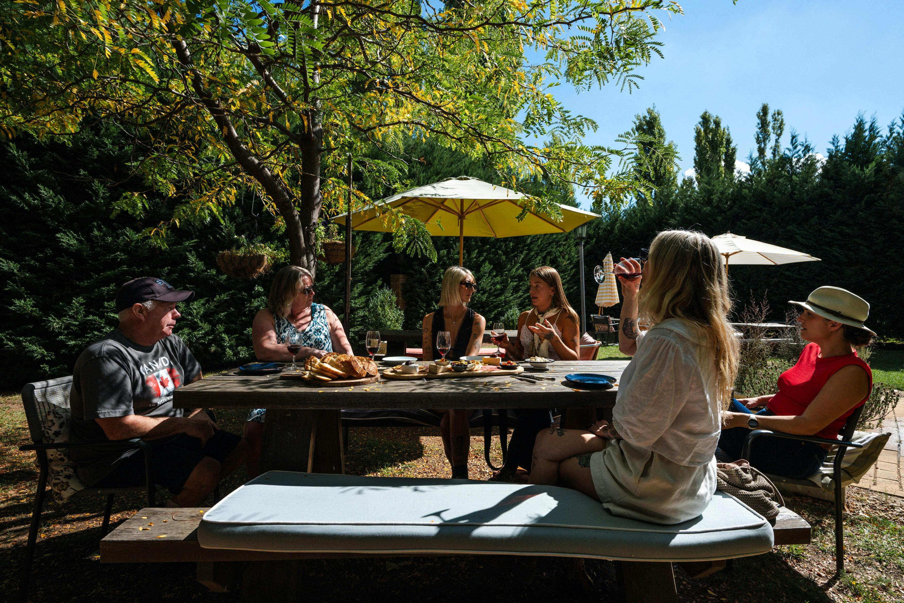 A small group of tour guests enjoying wine and cheese in a sunny courtyard