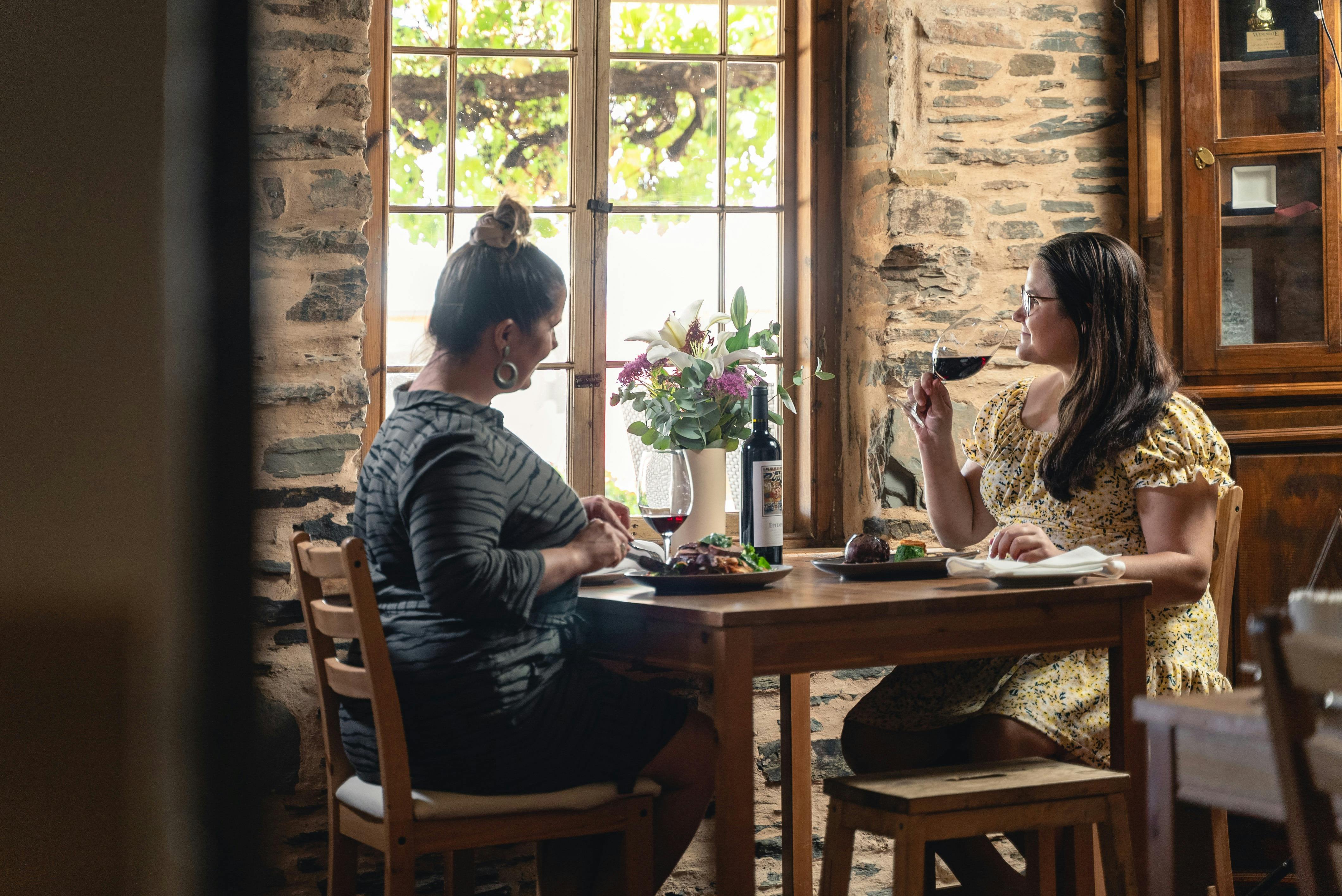 Two women sitting at a table in Reillys Heritage Restaurant enjoying gourmet meals and wine