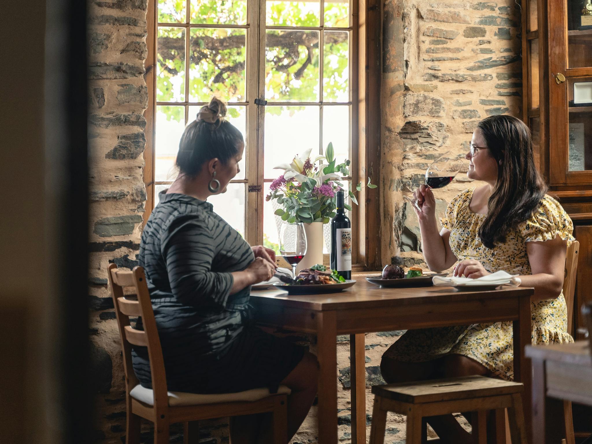 Two women sitting at a table in Reillys Heritage Restaurant enjoying gourmet meals and wine