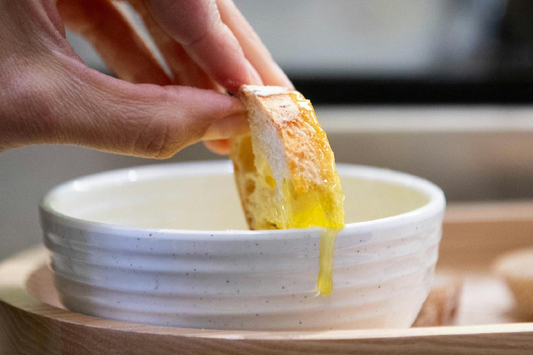 A hand holding bread dipped into sauce