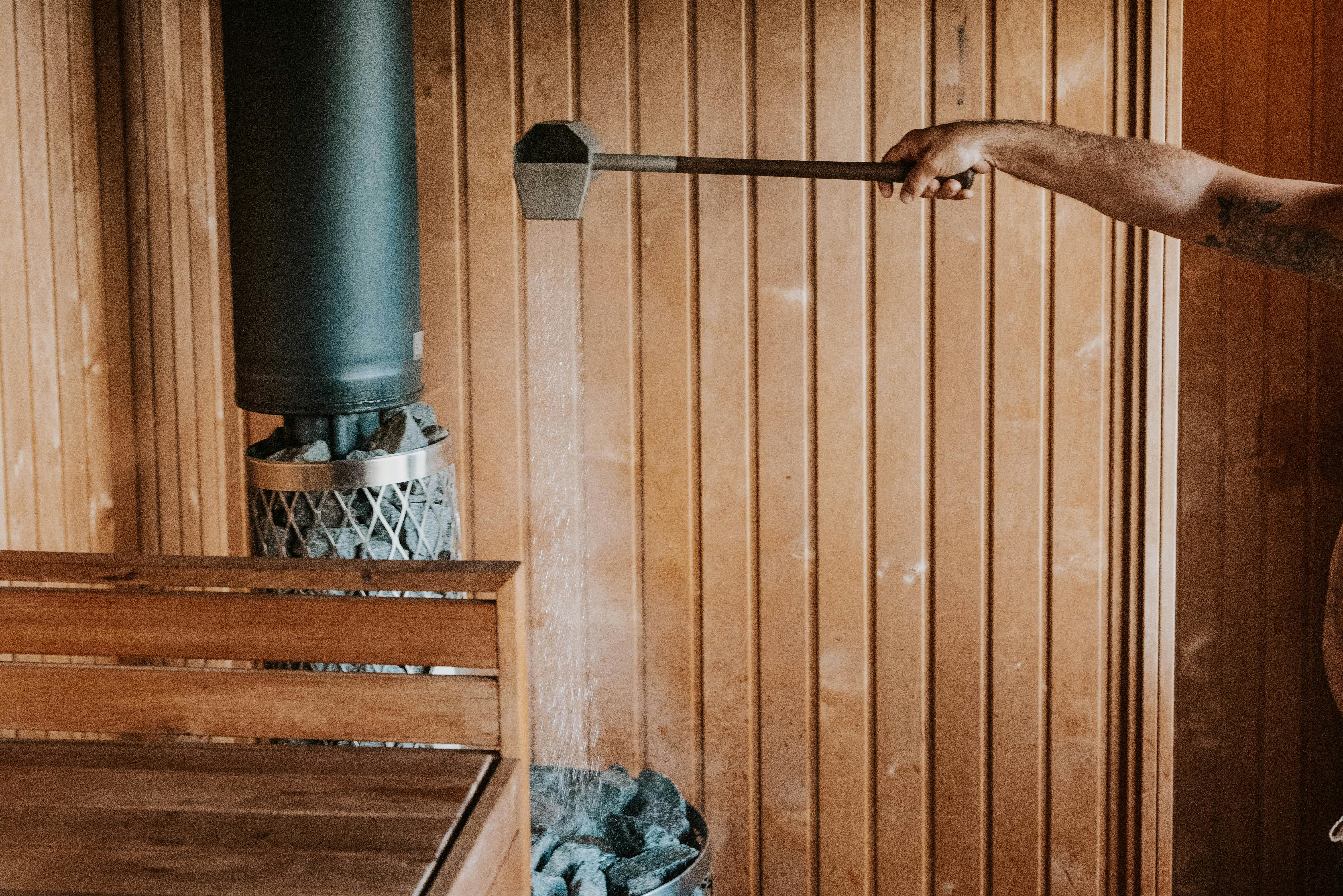 sauna master putting water on the rocks to create the loyly at cedar and salt