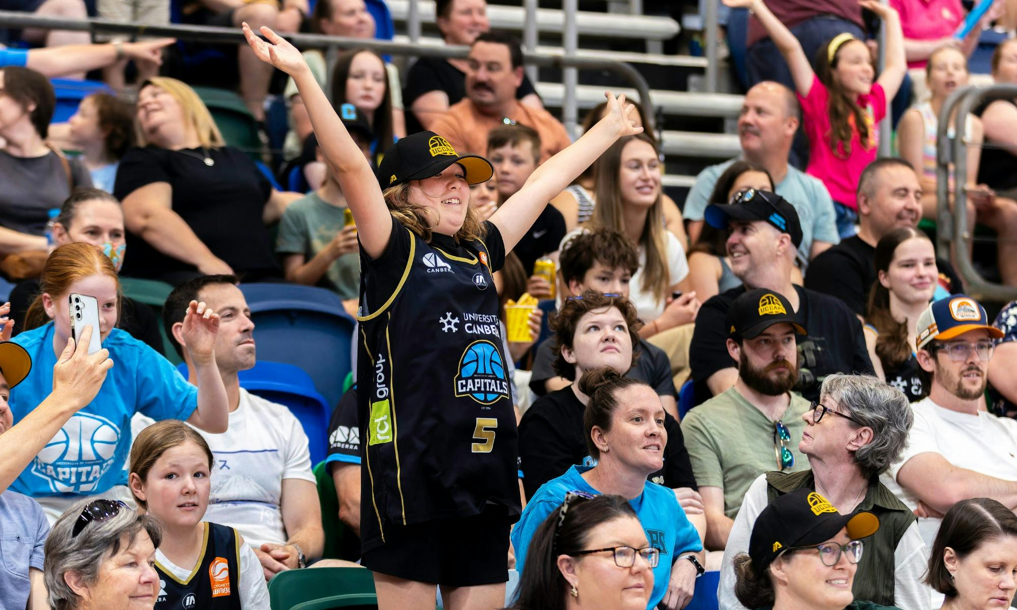 UC Capitals fan jumping and cheering in the crowd wearing Caps merch.