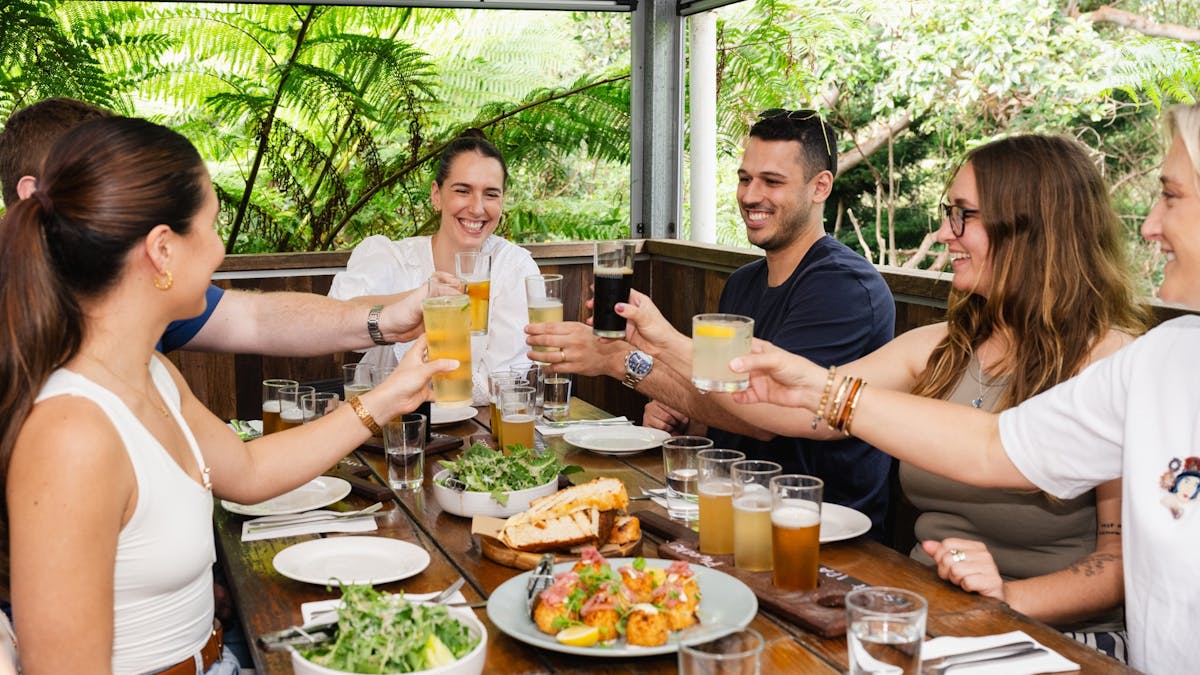 Group of friends cheers'ing drinks over spread of local food