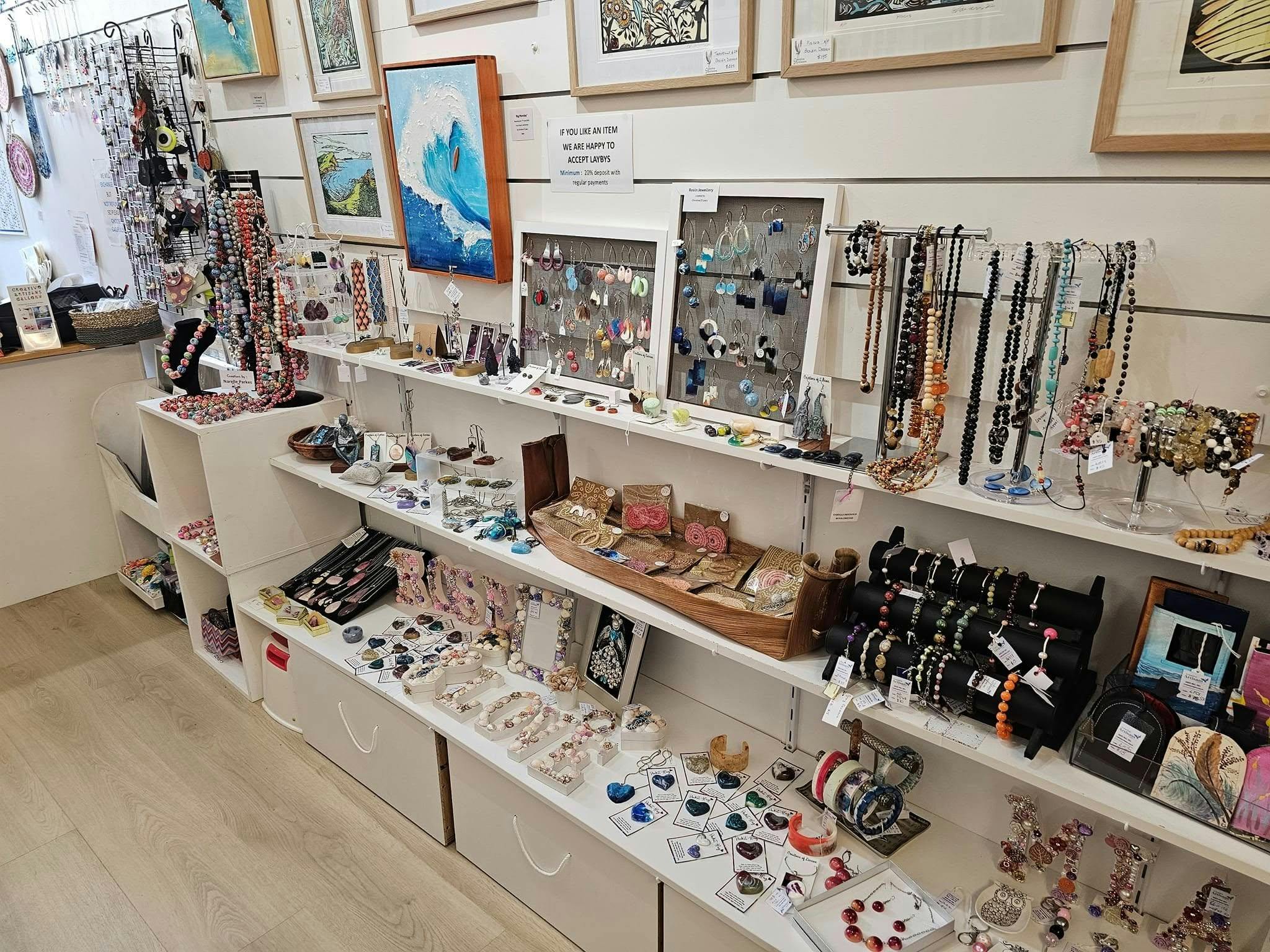 artworks, jewellery and other artistic creations displayed on white shelves