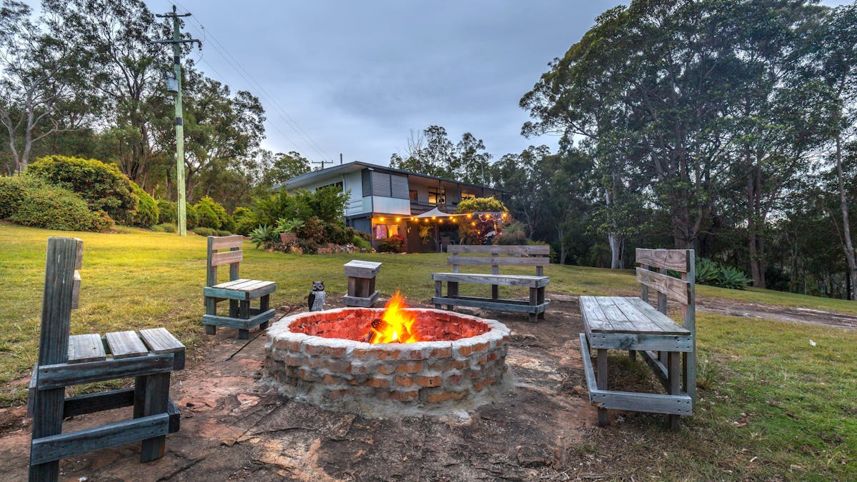 a firepit lit with seating around and house in the distance