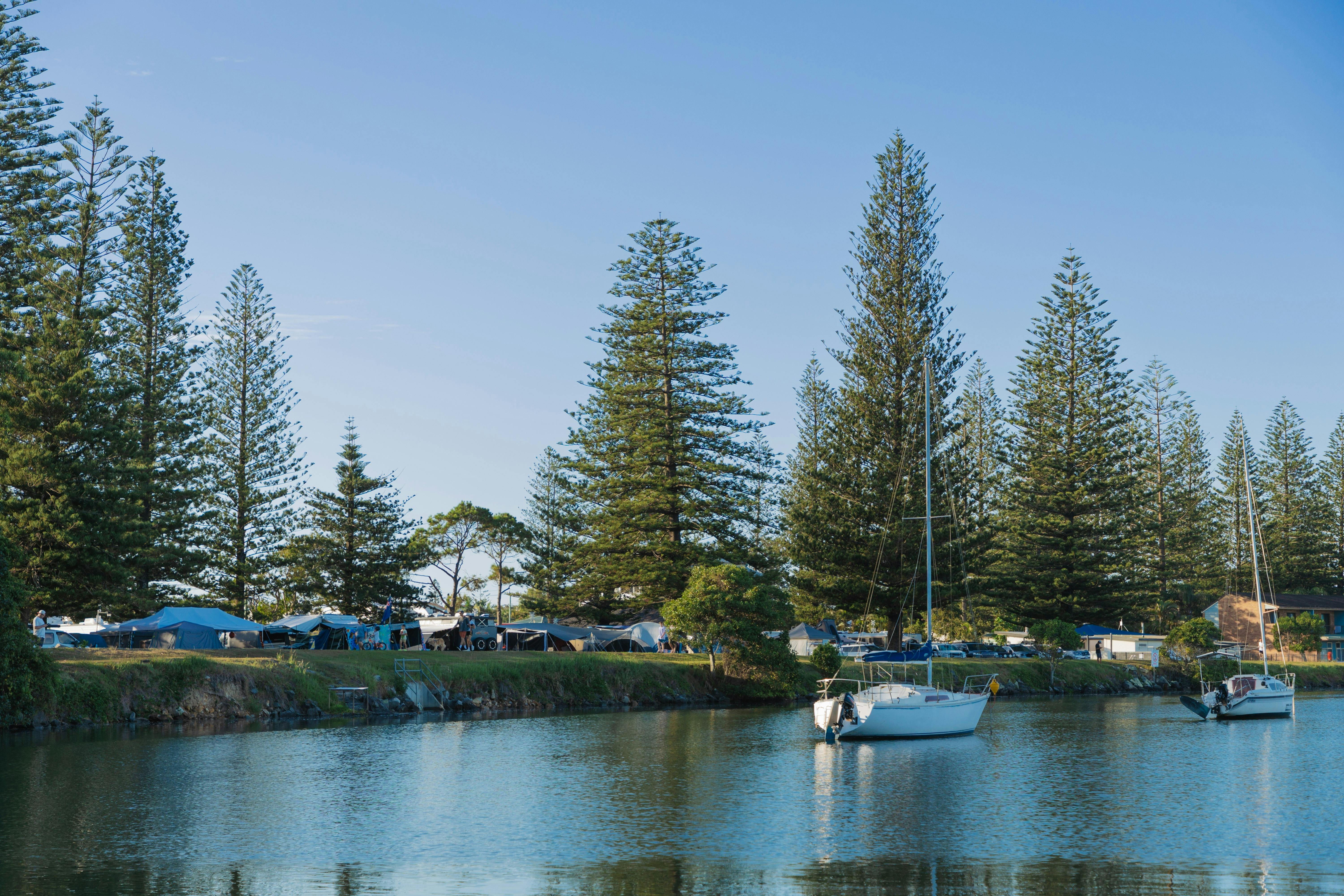 遊艇停泊在河中，河岸邊設有露營區。