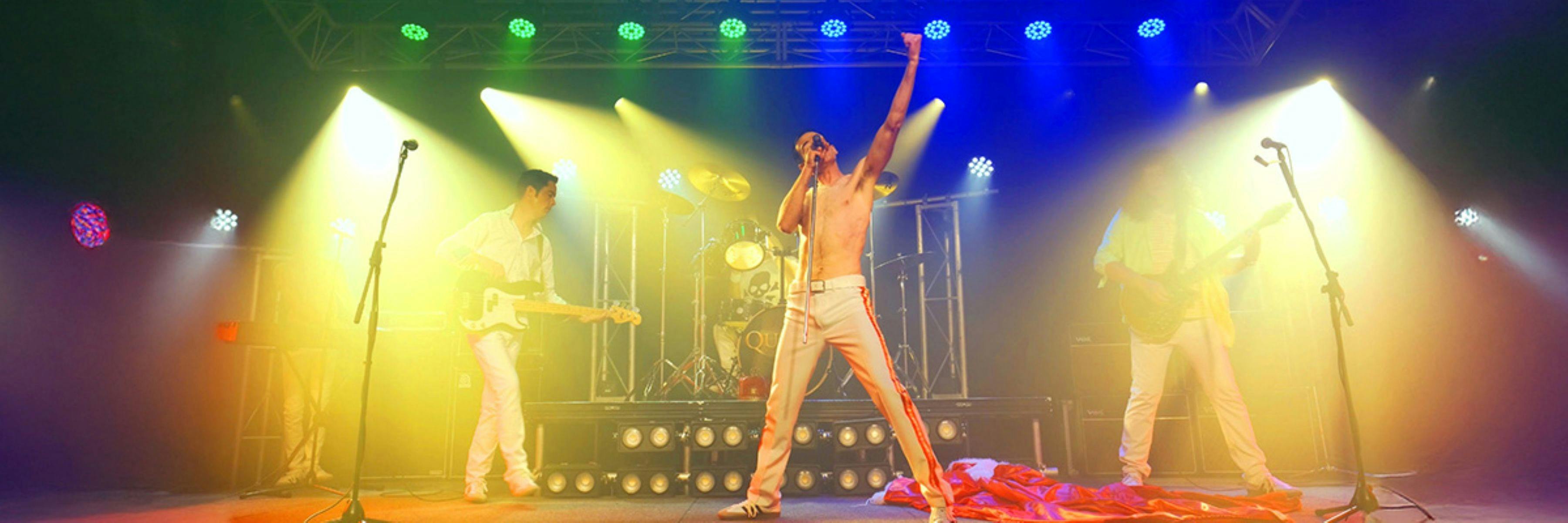 Two people playing guitars, one singer at a concert with coloured lights.