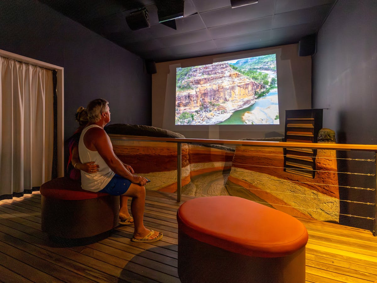 Couple in a darkened room watch a movie screen