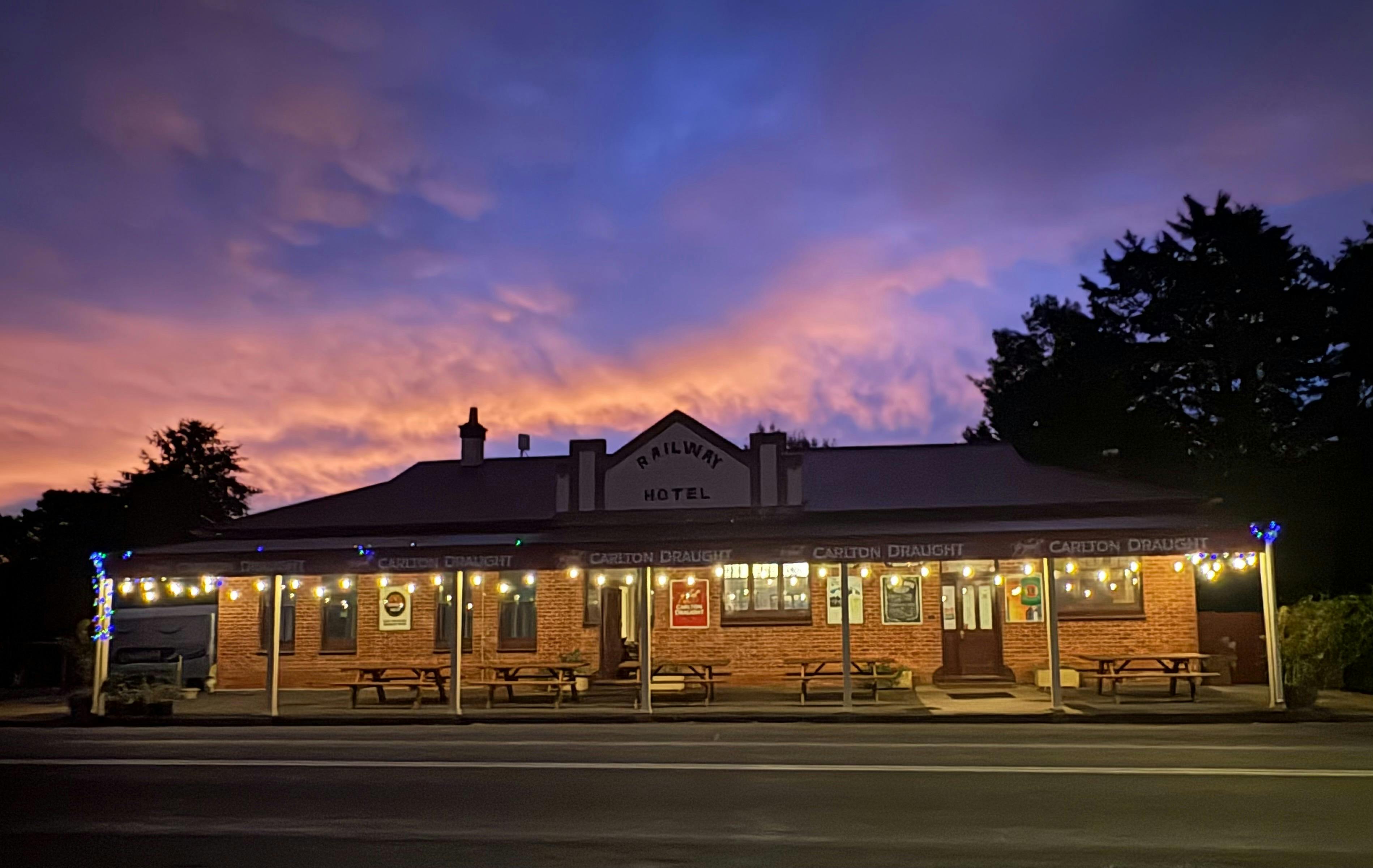 Das 120 Jahre alte Railway Hotel mit Lichtern vor dem Hintergrund eines rosa-violetten Sonnenuntergangshimmels.