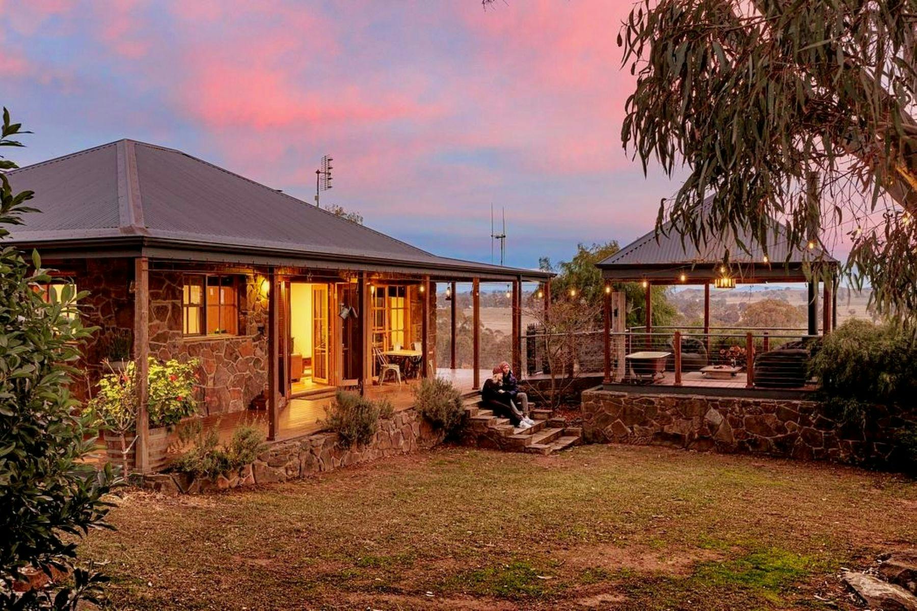 A loving couple sitting on the steps of Stone Creek Cottage at sunset