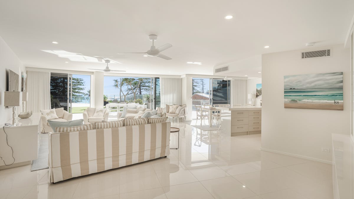 Inviting lounge with tan and white striped sofas, high-gloss tiled floors, and expansive oceanview