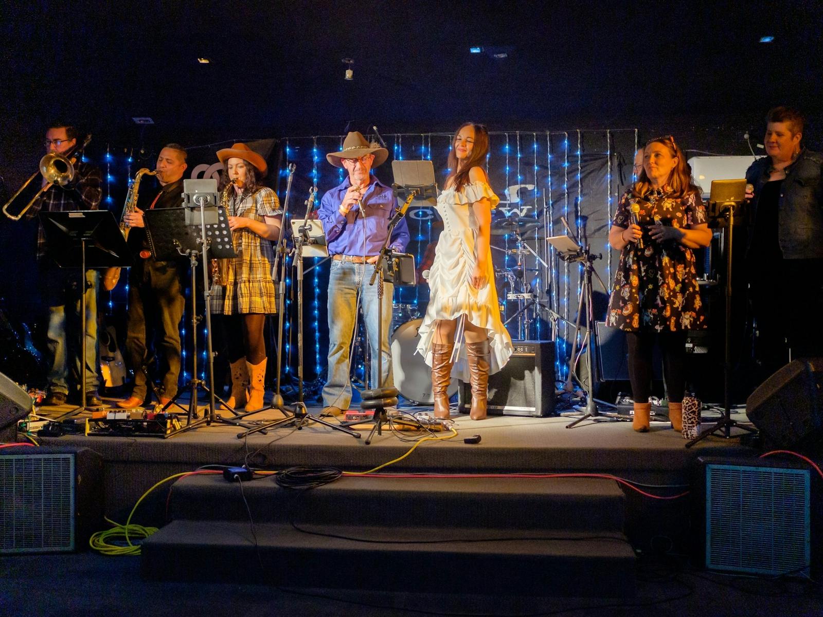 A band performing on stage with singers and instrumentalists A band performing on stage with singers and instrumentalists